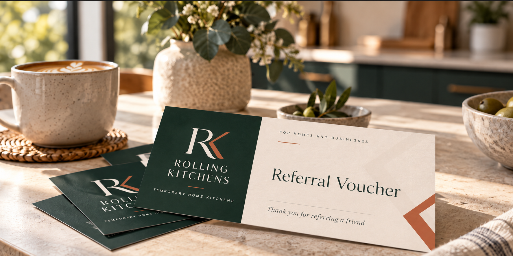 Referral vouchers from Rolling Kitchens on a kitchen table with coffee and plants.