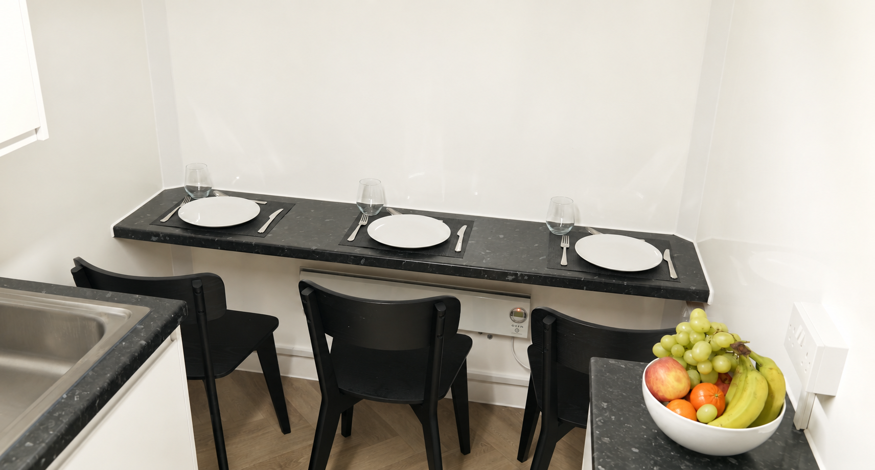 A table with three placemats, plates glasses and three chairs