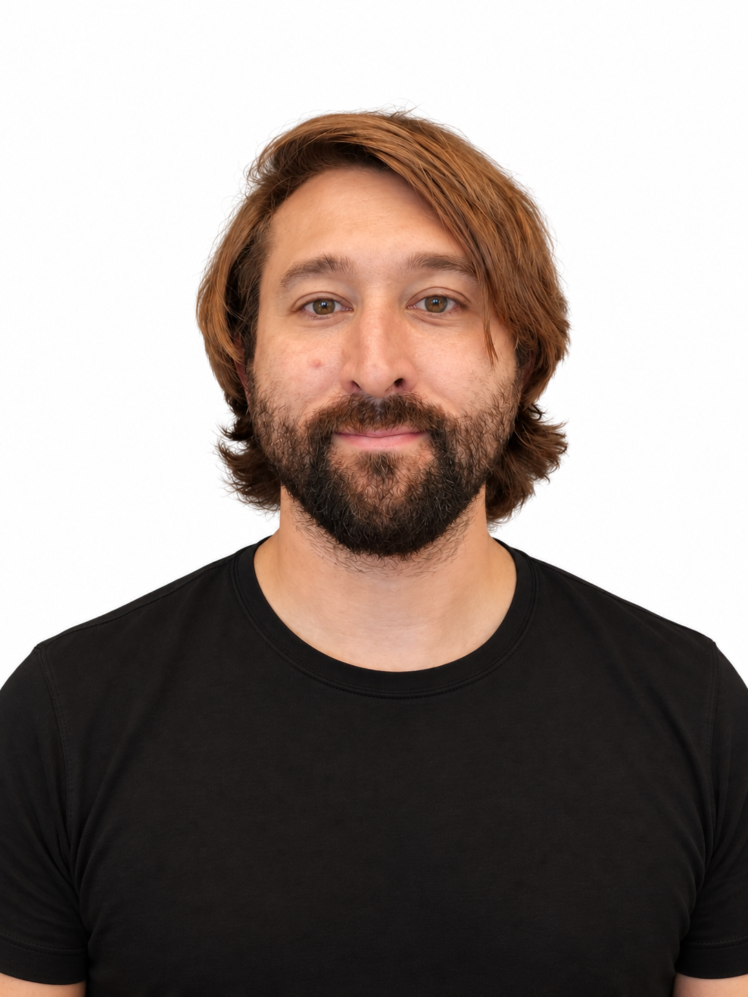 Portrait of a man with shoulder-length brown hair, a beard, and mustache, wearing a black t-shirt, smiling slightly, against a white background.