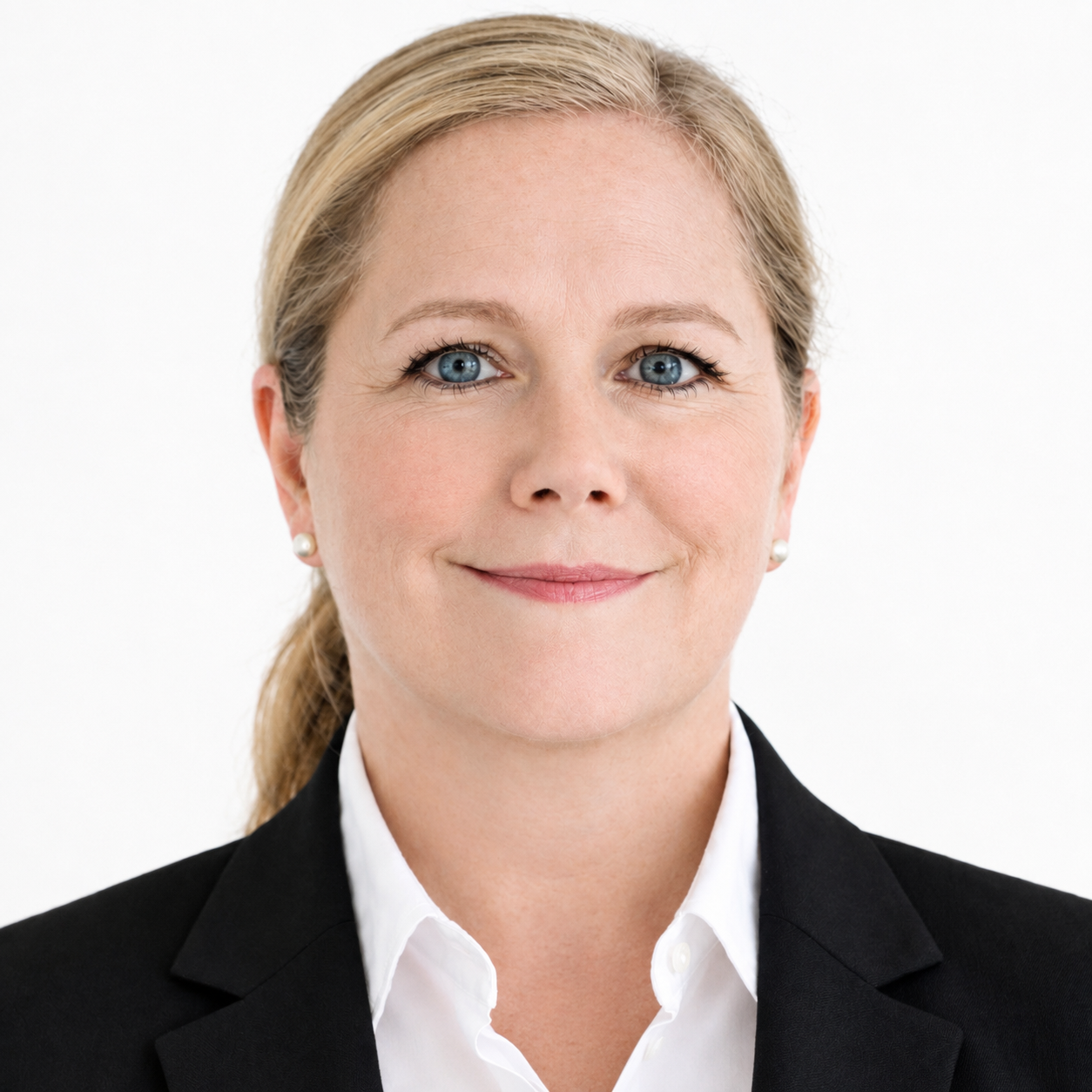 Porträt einer professionellen Frau mit blauen Augen, blonden Haaren und einem freundlichen Ausdruck, trägt eine schwarze Blazer und weisse Bluse, gegen weißen Hintergrund.