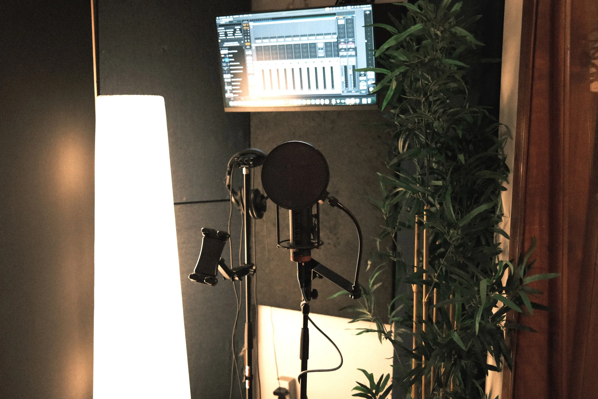Mise en place d'un micro, d'un anti-pop et d'un pied de micro dans la salle d'enregistrement de musique du Studio Agora.