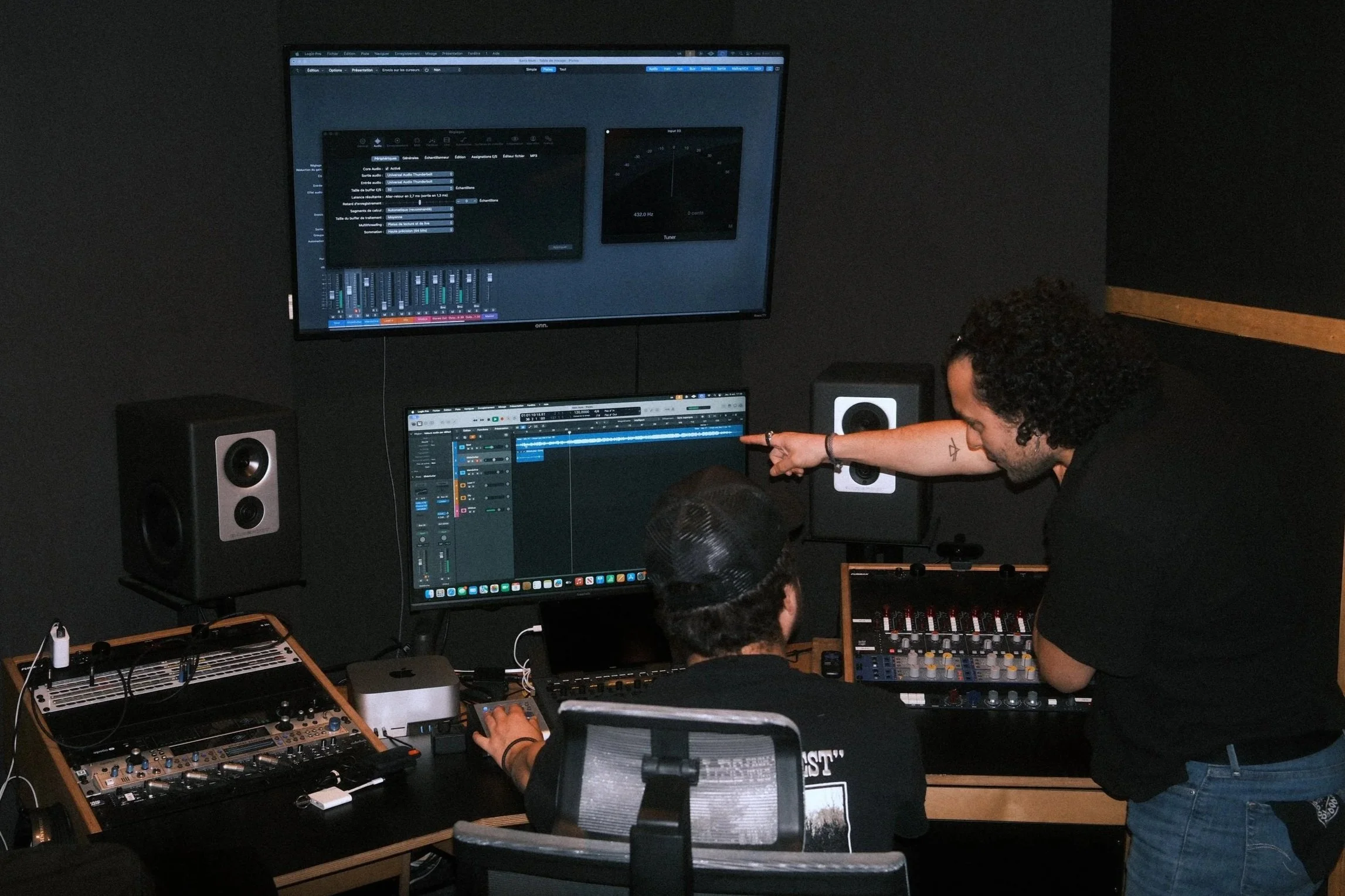 Un ingénieur du son et un artiste en train d'échanger sur la composition d'une production musicale dans la control room