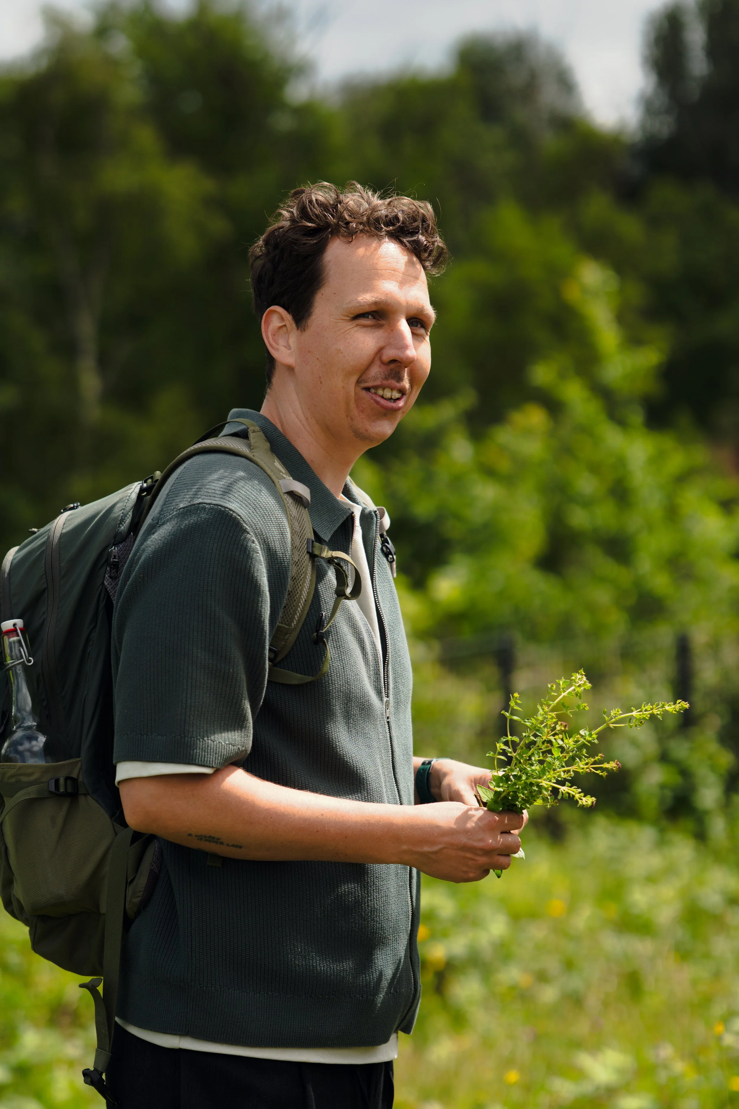 Man met een rugzak die een plant vasthoudt tijdens een wandeling in een bos