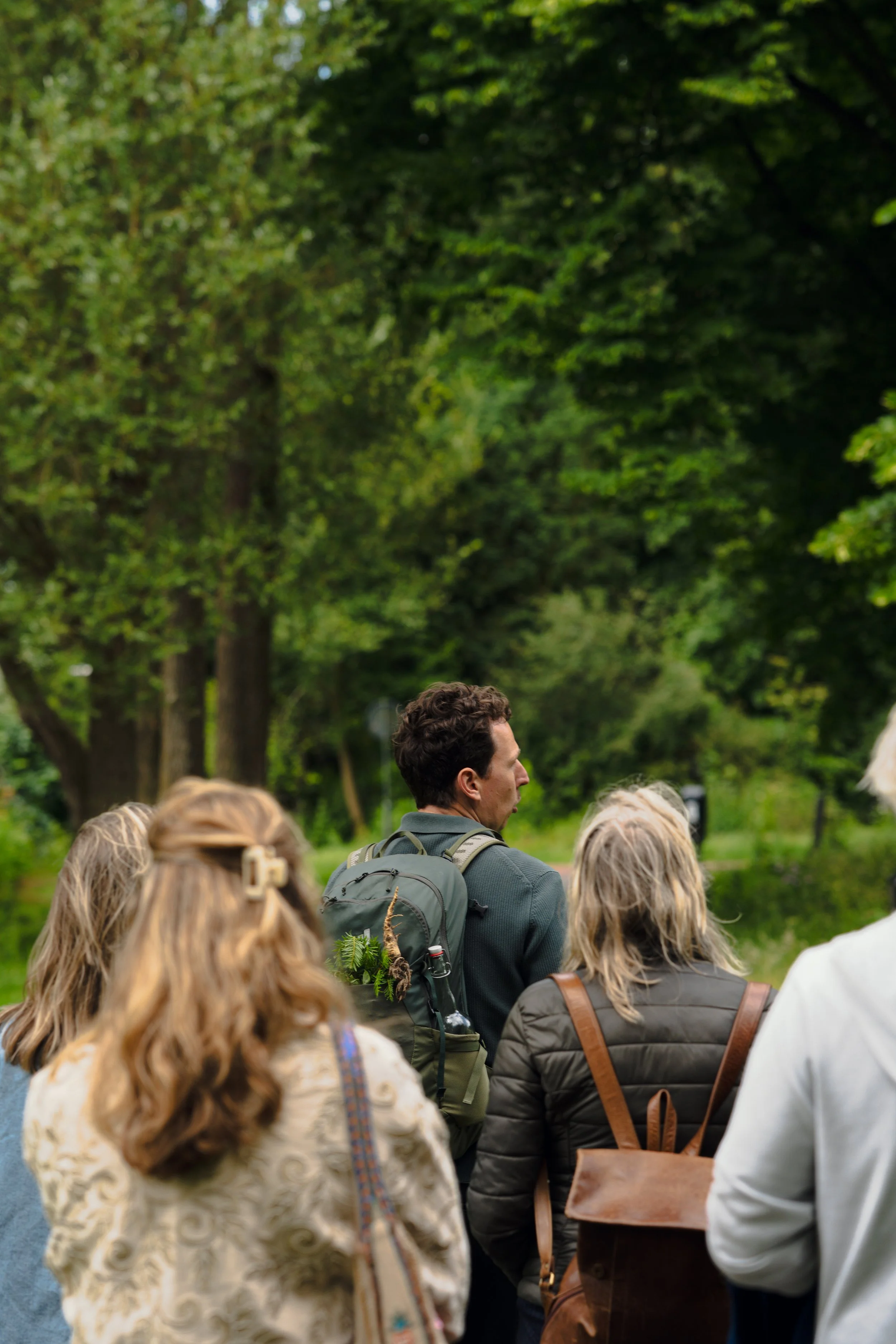 Mensen die in een park of tuin samen staan, omringd door groene bomen.