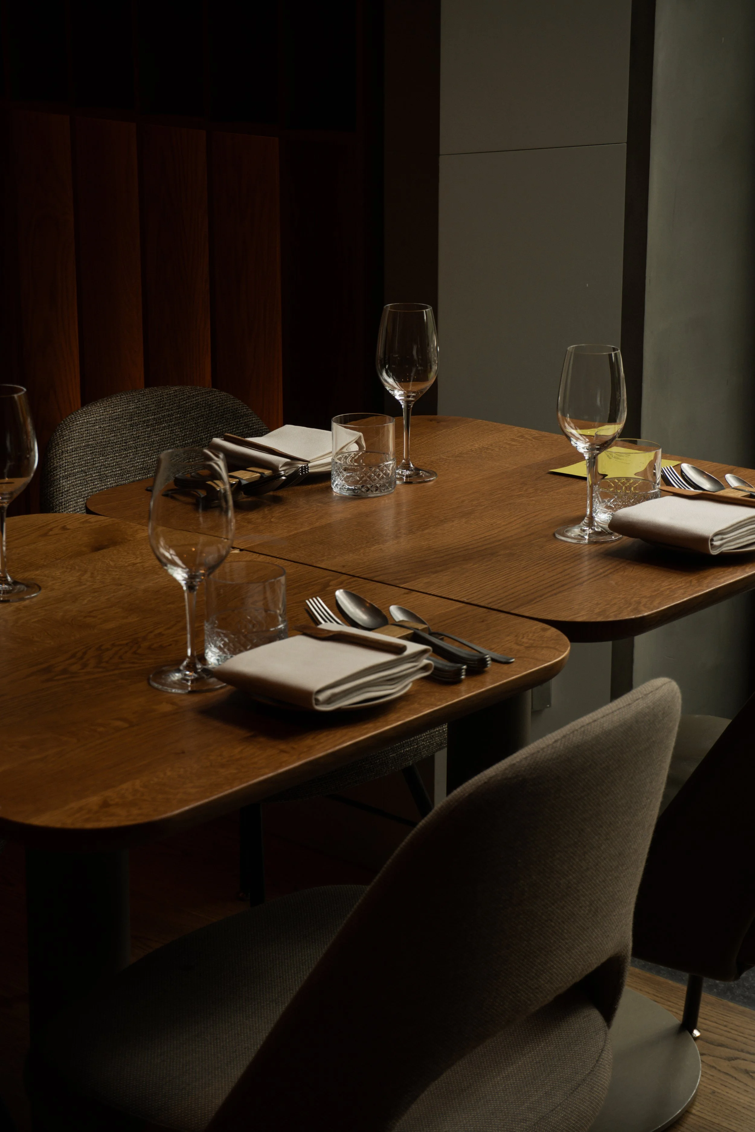 Een restaurant tafel klaar voor een maaltijd met wijn, water en bestek, omgeven door comfortabele stoelen in een moderne, rustige eetruimte.