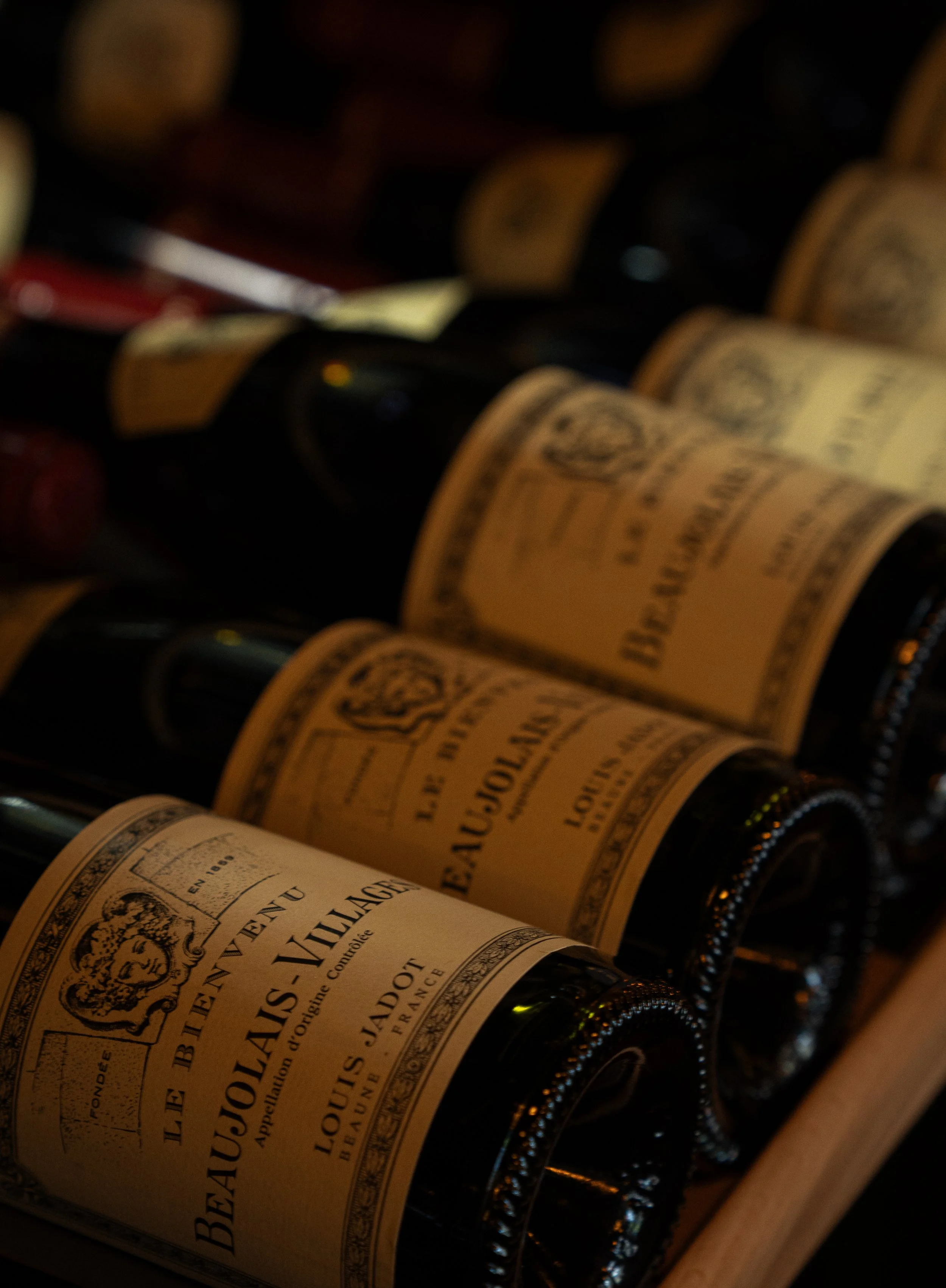 Close-up van wijnflessen met champagnelabels in een wijnrek, lage belichting.