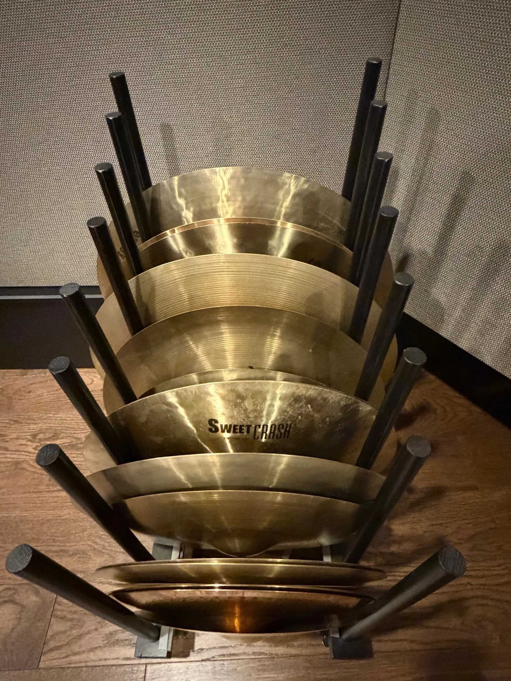 A stack of circular, metallic trays, with the top tray labeled 'Sweet Cash,' and they are leaning against a textured wall.
