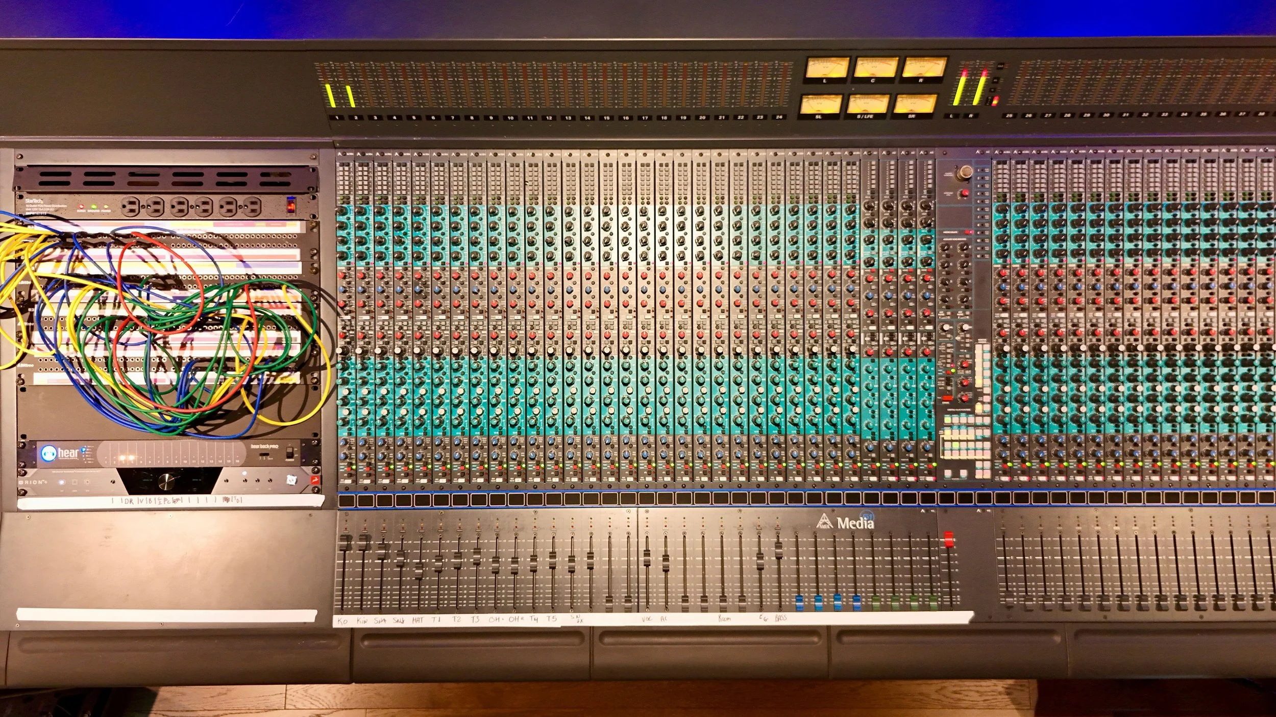 A professional audio mixing console with multiple channels, knobs, faders, and colorful connected wires.