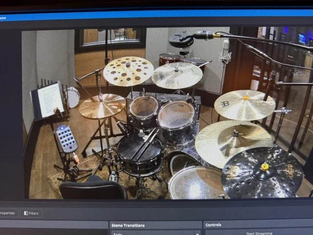 A drum set with multiple cymbals, drums, and drumsticks in a recording studio.