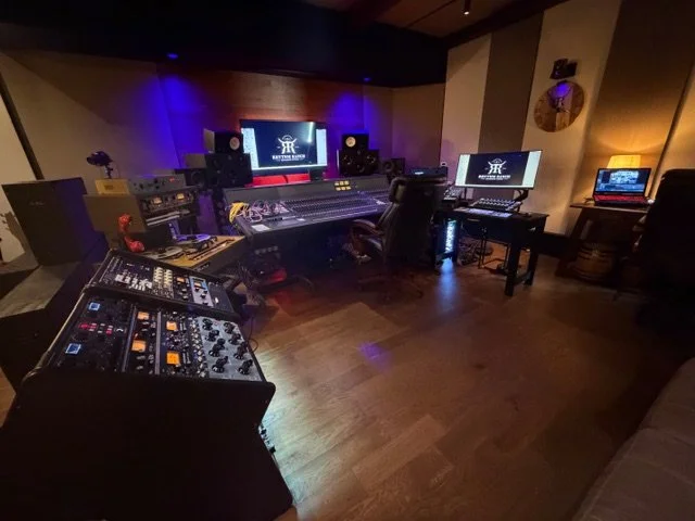Music recording studio with mixing console, speakers, computer monitors, and audio equipment.