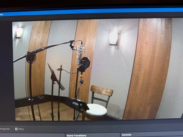 Recording studio with microphone, pop filter, music stand, chair, and wall-mounted lights.
