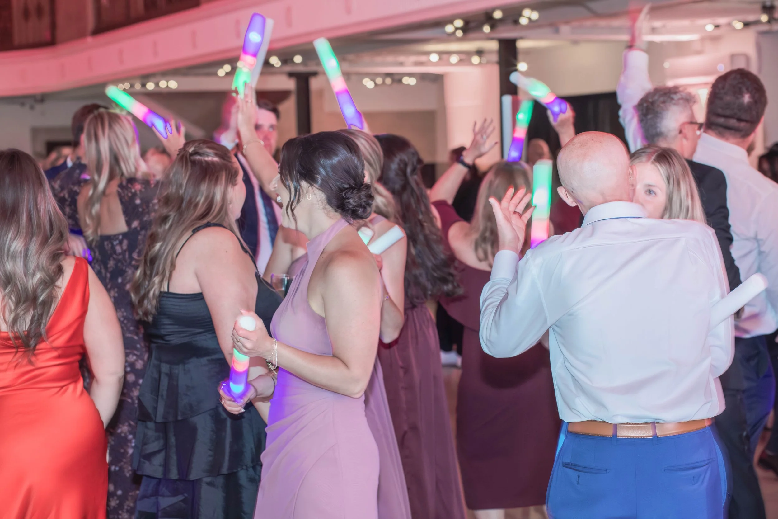 Wedding guests packing the dance floor with light-up foam sticks at a NightBeat Entertainment reception