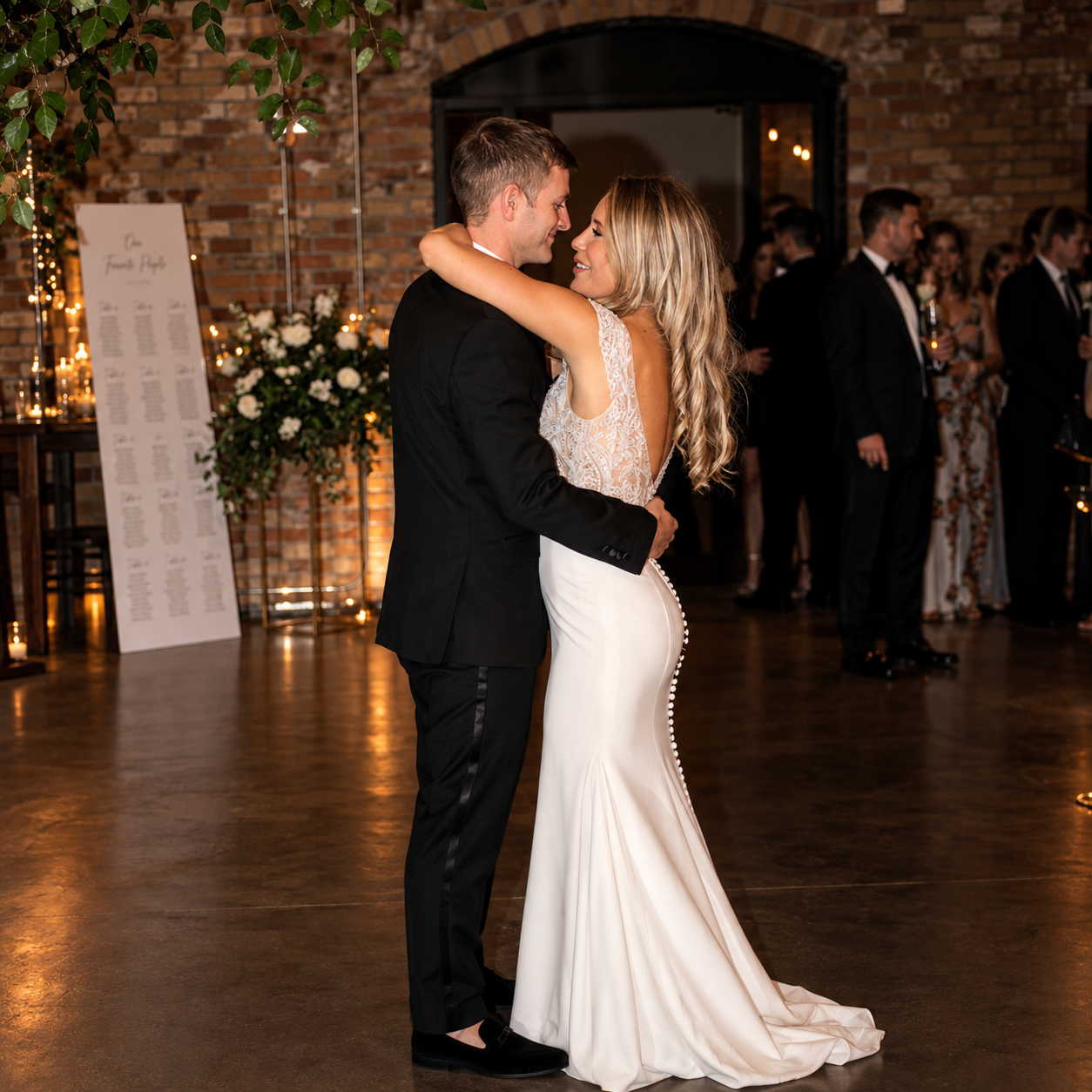 Bride and groom embracing during their first dance under brick arches at a NightBeat wedding