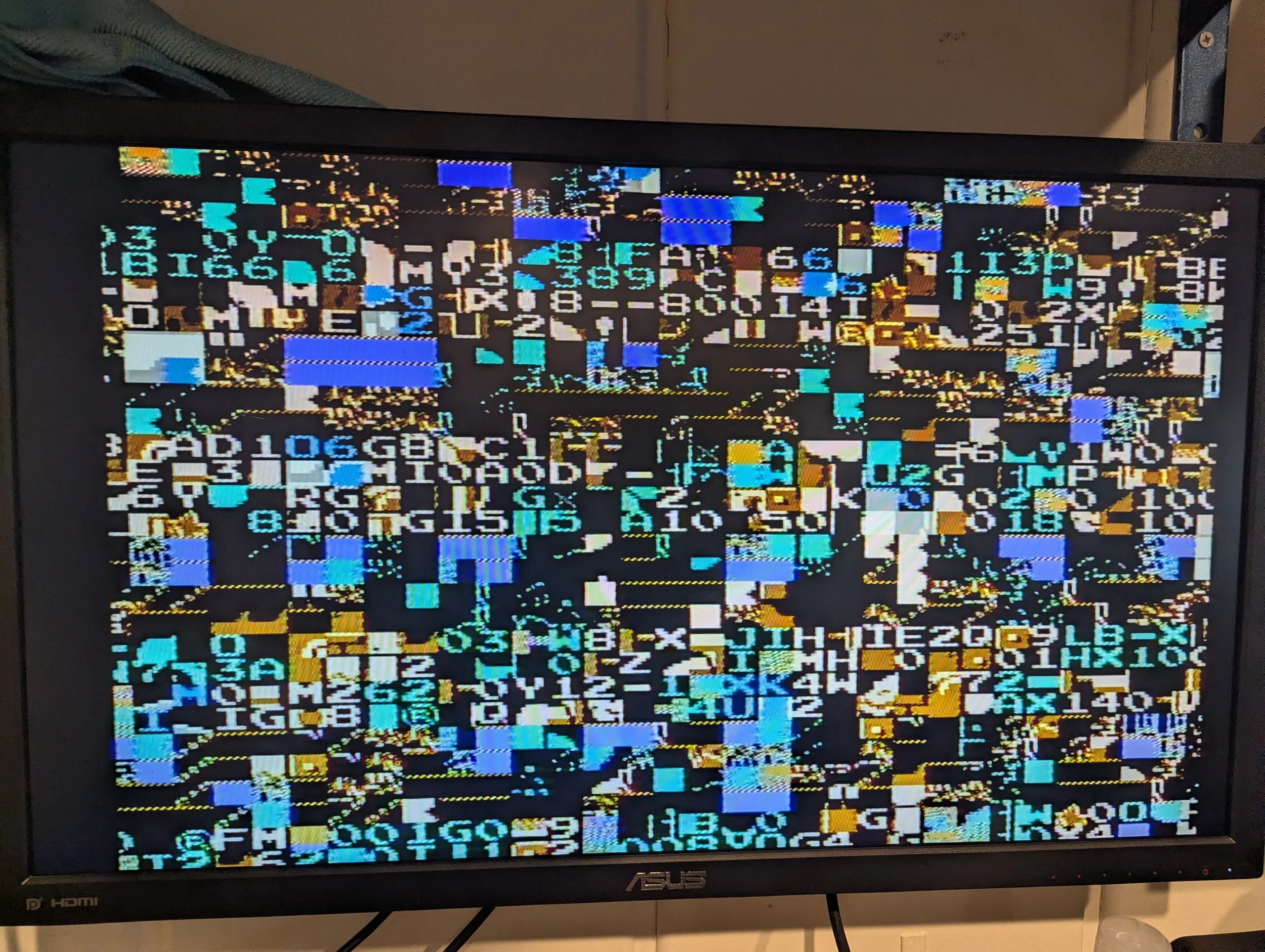 A computer monitor displaying a screen with severe graphical distortion and pixelation, showing random colors, shapes, and alphanumeric characters.