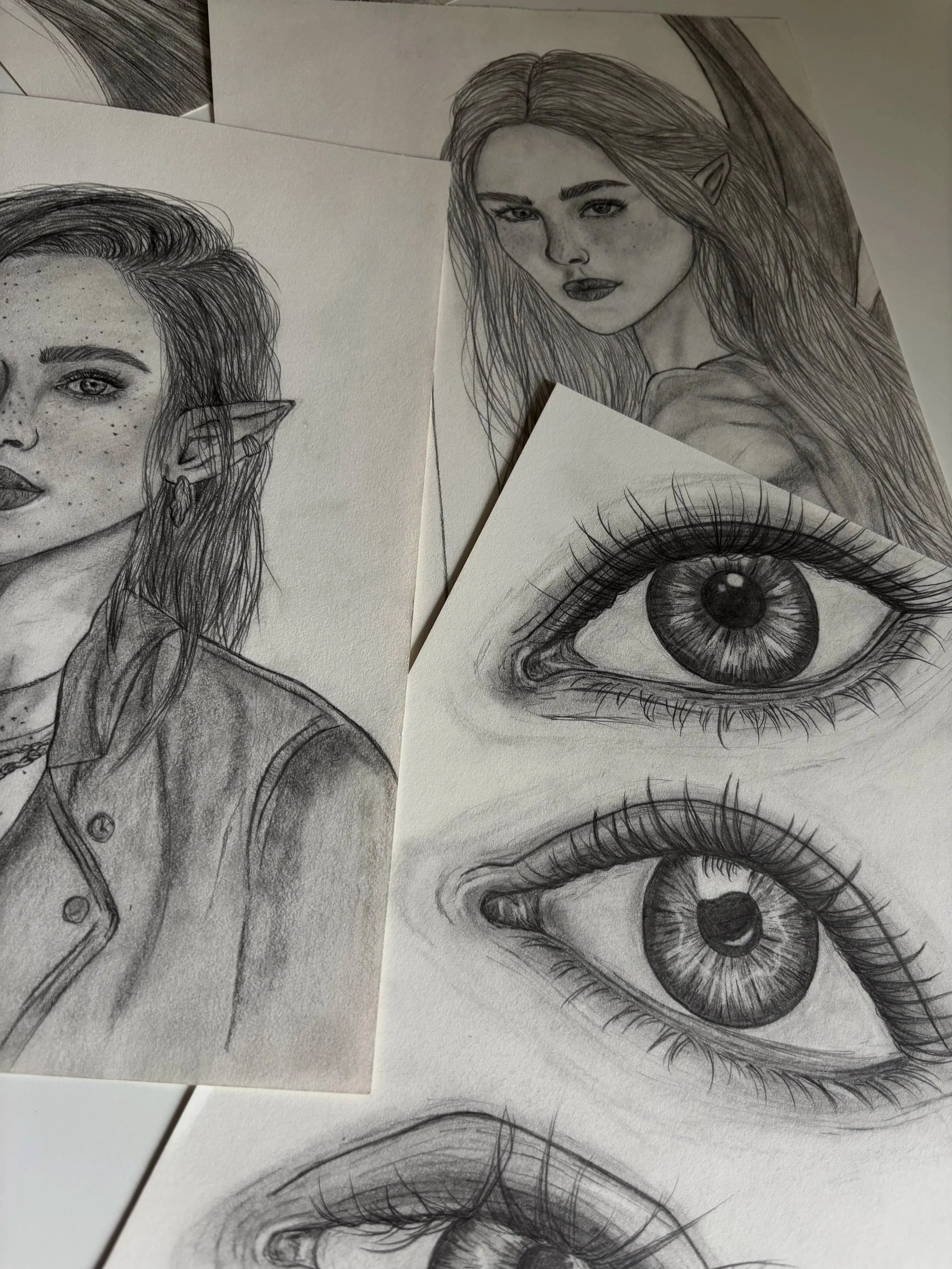 Skizzierte Porträts und Augen, merkmale von Fantasy-Charakteren und realistischen Darstellungen auf Papier