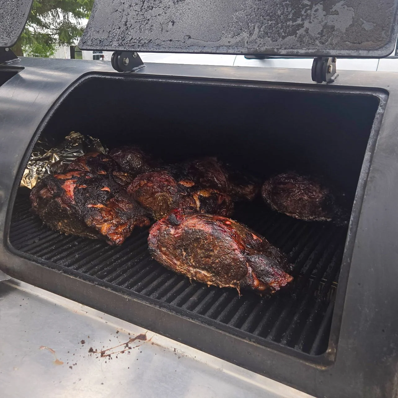 Barbecue smoker with several smoked beef briskets cooking inside.