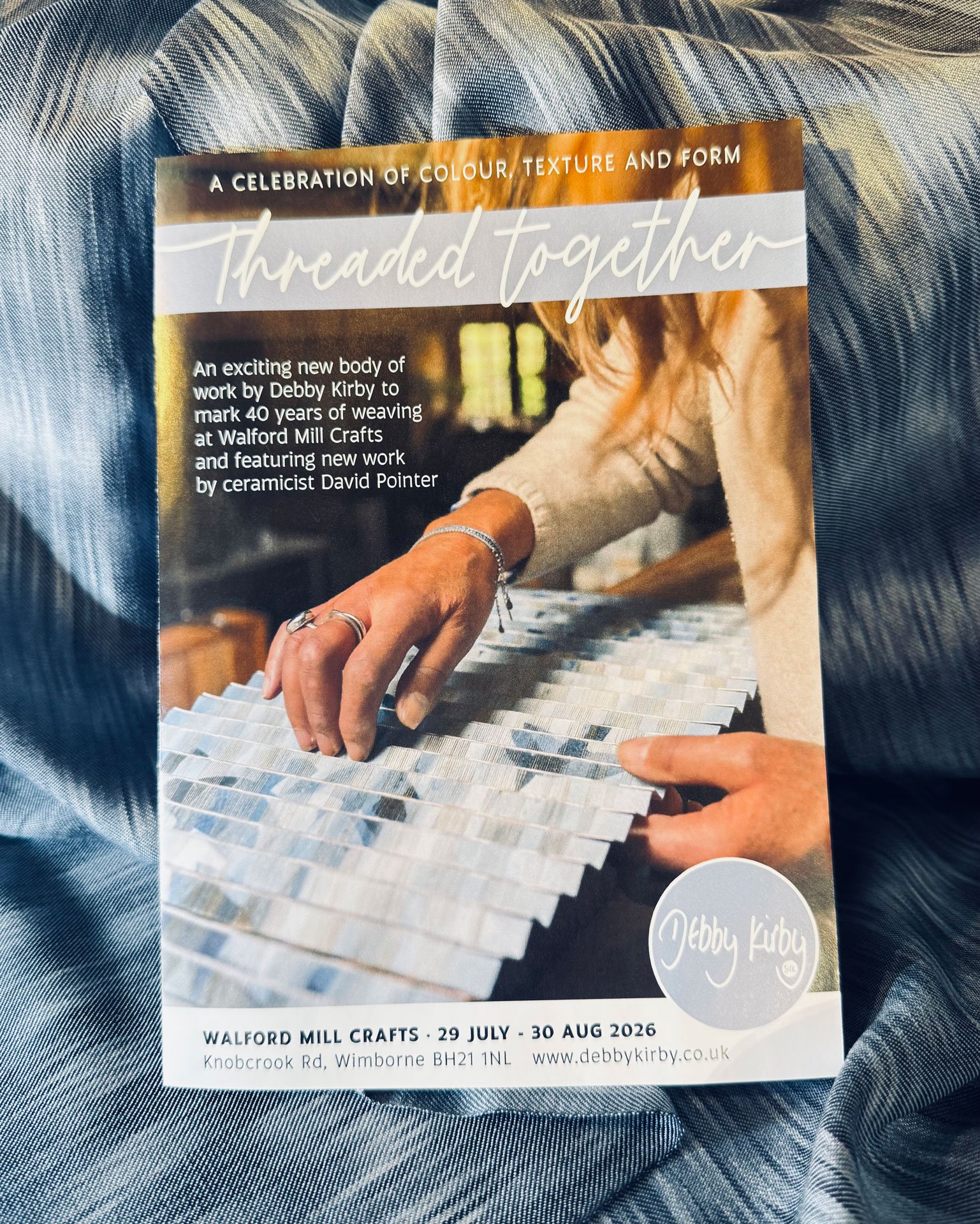 A promotional flyer for an event called 'Threaded Together' at Walford Mill Crafts, scheduled from July 29 to August 30, 2026. The flyer features an image of a person working with a palette of fabric samples, with details about the event and location.