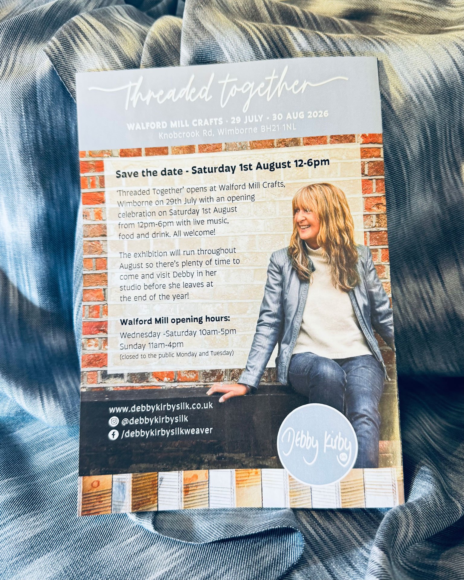 A flyer for an event called 'Threaded Together' at Walford Mill Crafts on July 29 to August 30, 2026, featuring an opening celebration on August 1st from 12-6pm with live music, food, and drinks. The flyer shows a smiling woman with long blonde hair in a casual outfit, sitting against a brick wall. The flyer includes the website www.debbykirbysilk.co.uk and social media handles.