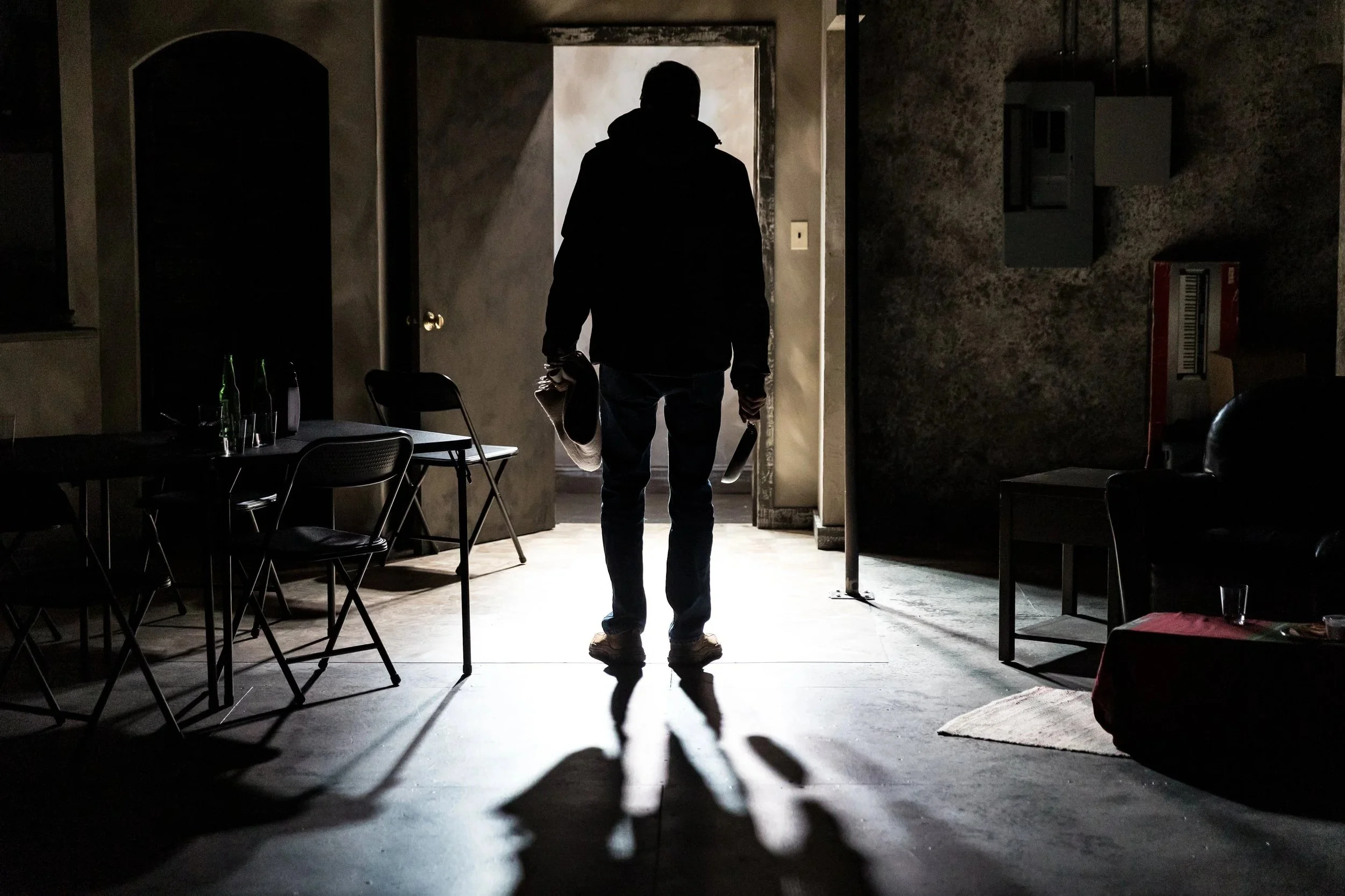 A figure silhouetted in a brightly lit doorway casts a long shadow in The Humans, Park Square Theatre, 2022. Lighting by Karin Olson.