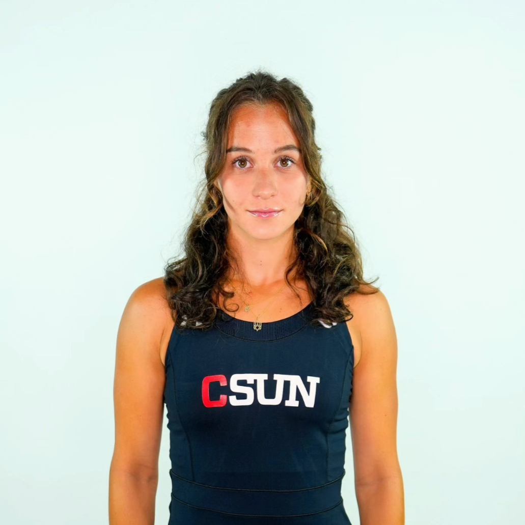 Young woman with curly brown hair wearing a navy athletic top with 'CSUN' logo, standing against a plain light background.
