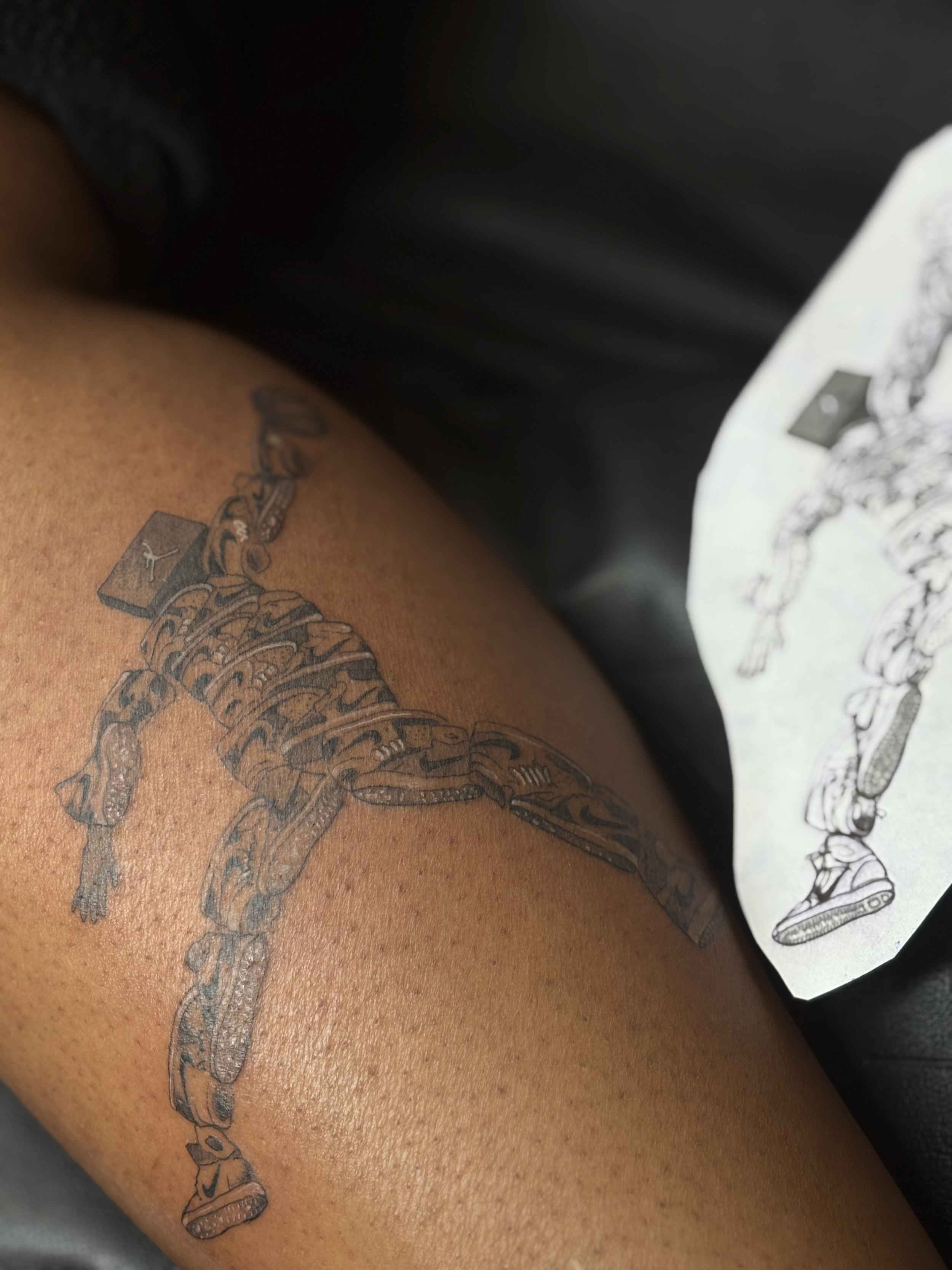 Tattoo of a custom Jordan emblem, made out of sneakers on outer calf. 