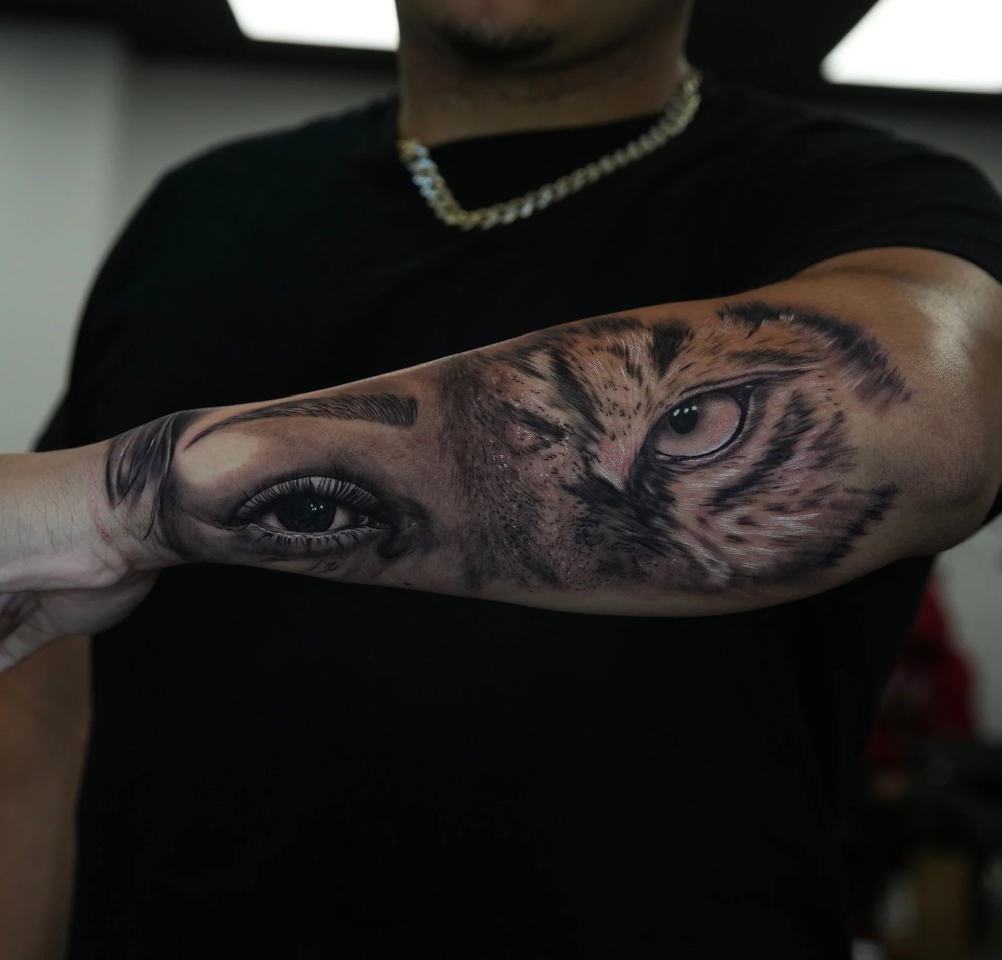 Close-up of a forearm tattoo with detailed set of eyes, partially human mothers eye; another tiger eye.
