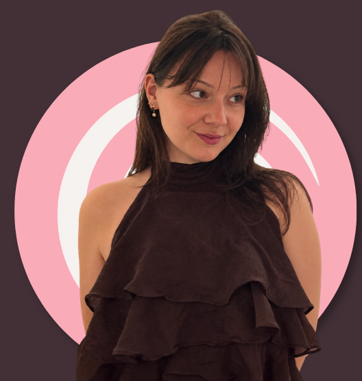 A woman with brown hair and earrings posing in front of a pink and white spiral background.