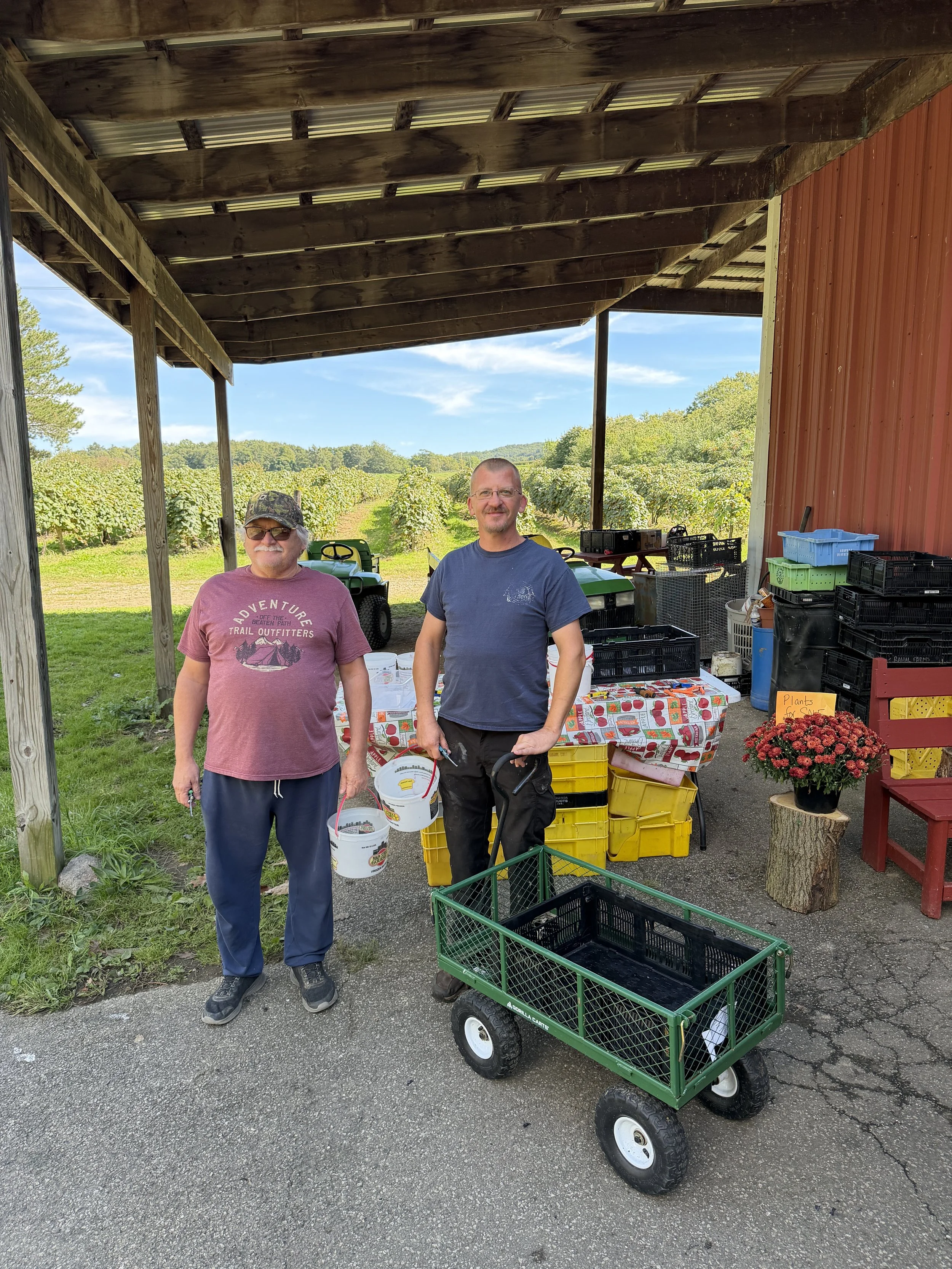 two men with buckets at farm stand.jpeg