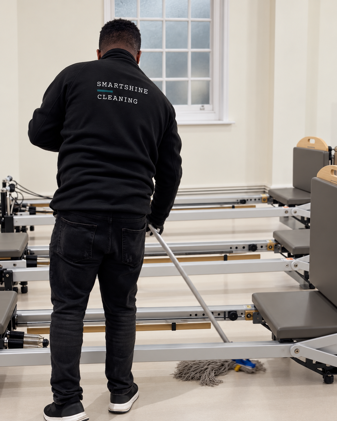 Smart Shine cleaner mopping the floor between Pilates reformers