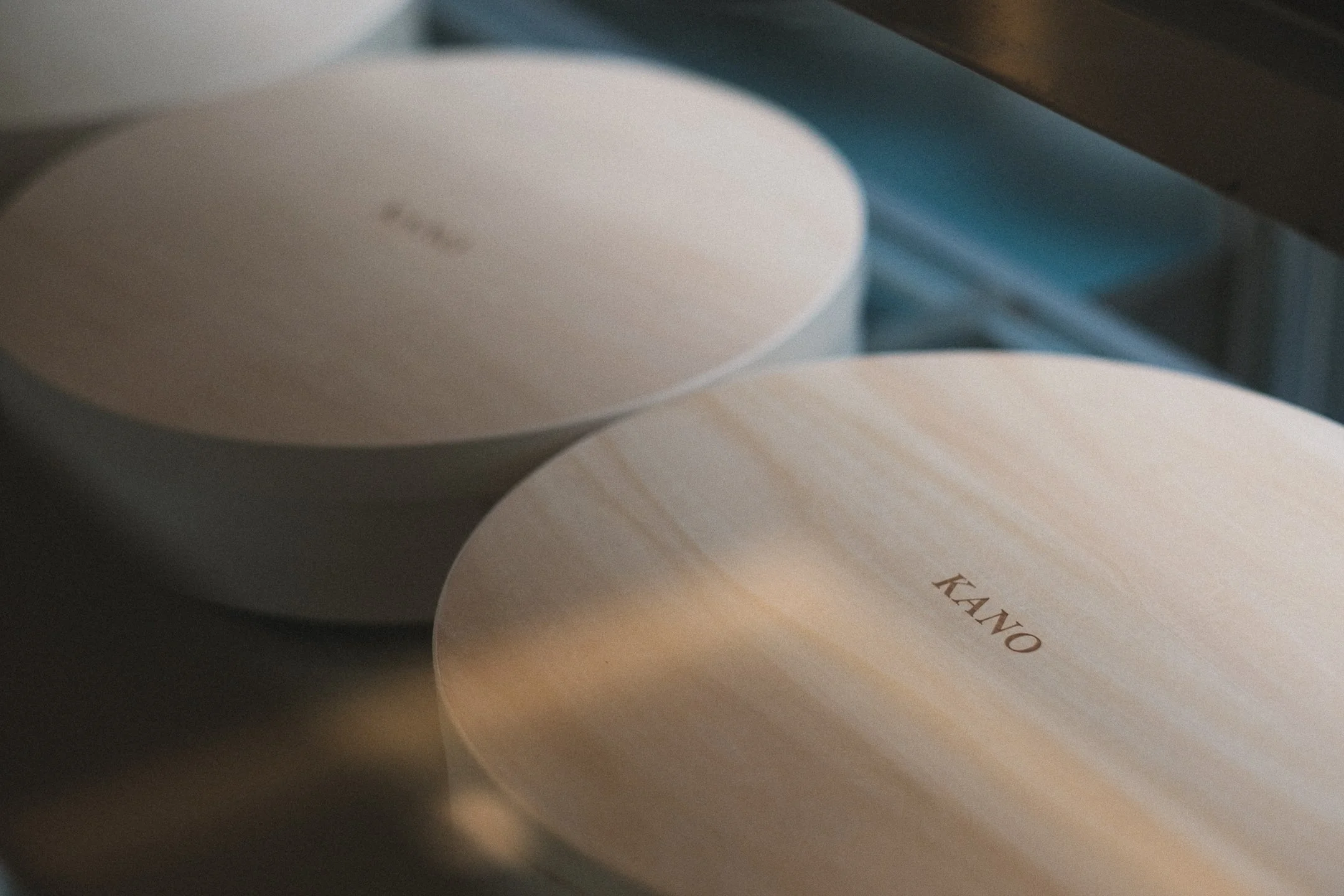Close-up of round sushi boxes with minimalist design, featuring the word "KANO" on the lids.