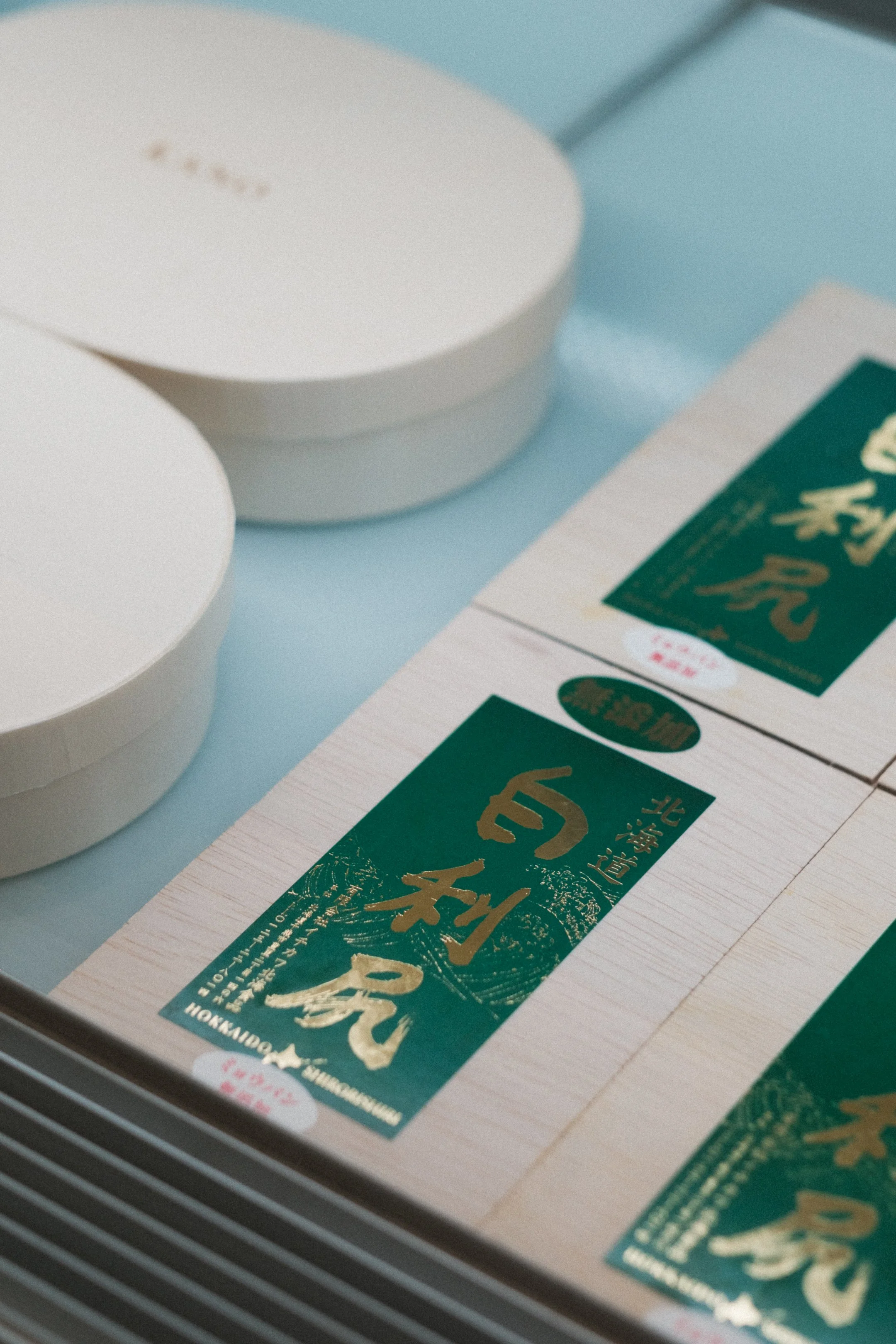 Close-up of several boxes of Hokkaido uni (sea urchin) in green and gold packaging.