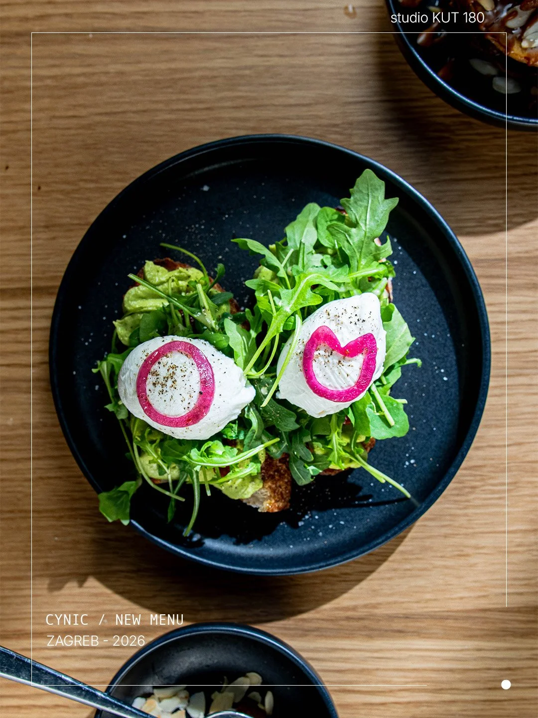 Salad with arugula, two poached eggs with pink ring and heart carved in radish, served on a black plate