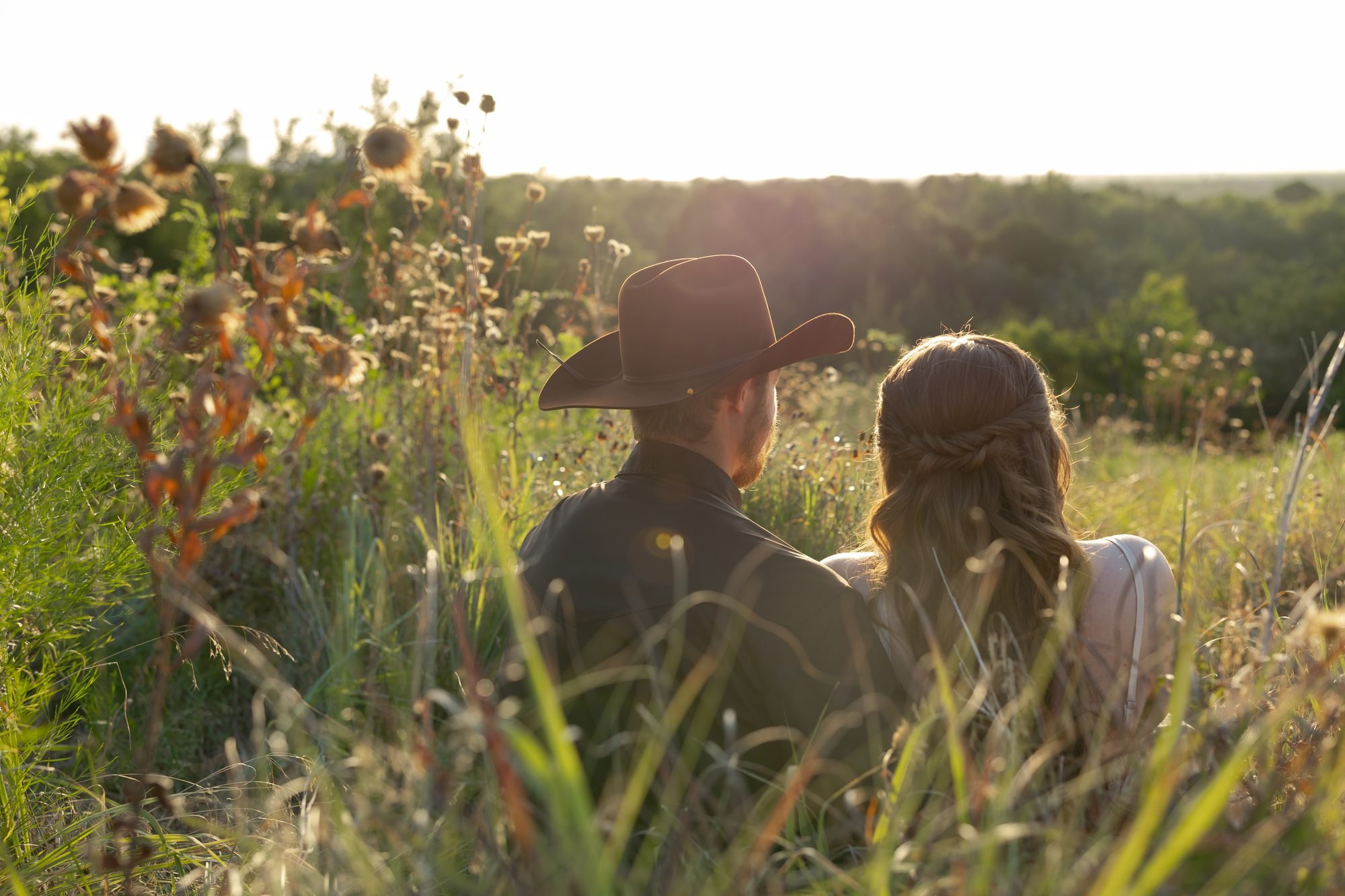 Couple sitting in wildflowers at sunset during a Texas engagement session