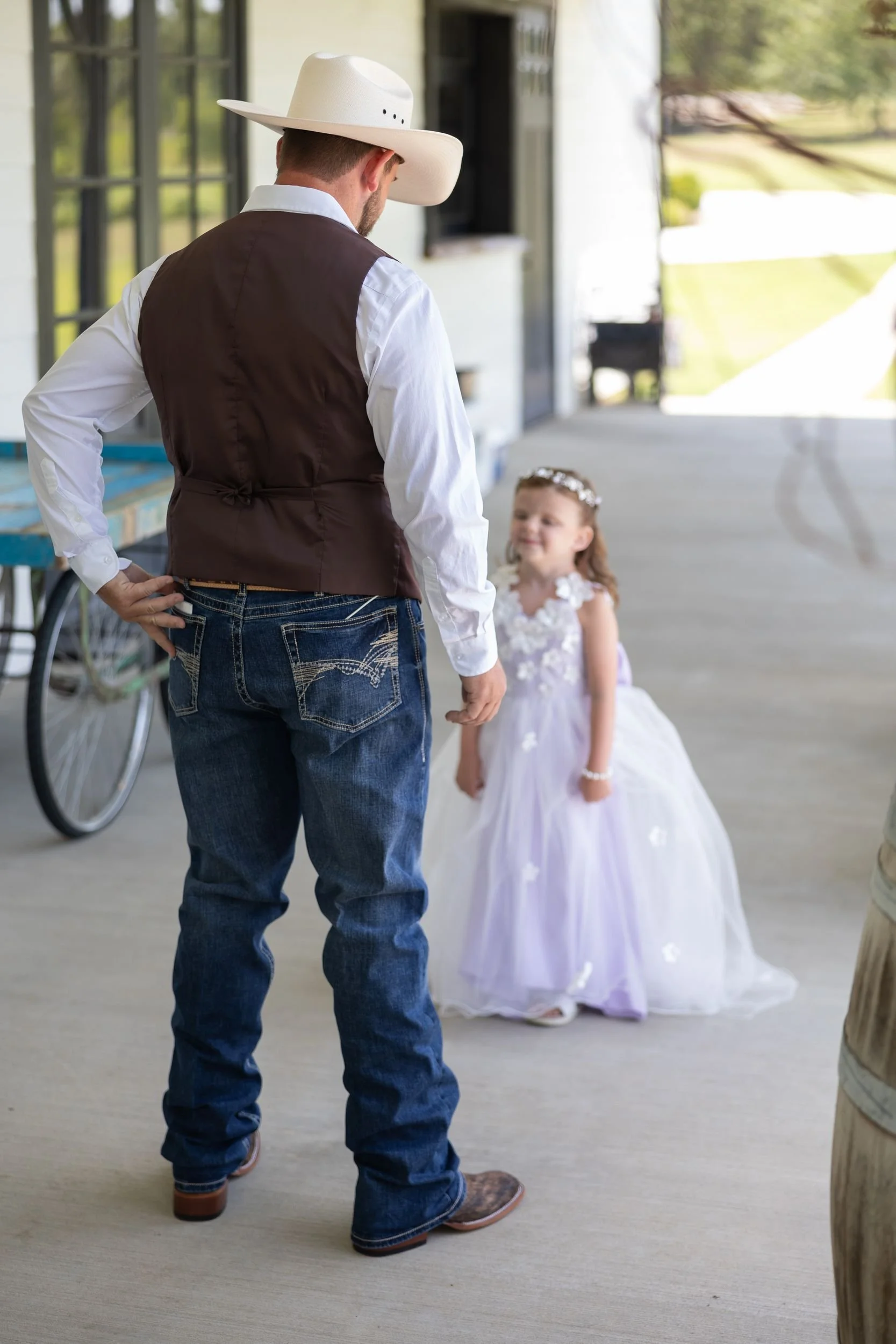 Groom in a cowboy hat with the flower girl in a lavender dress