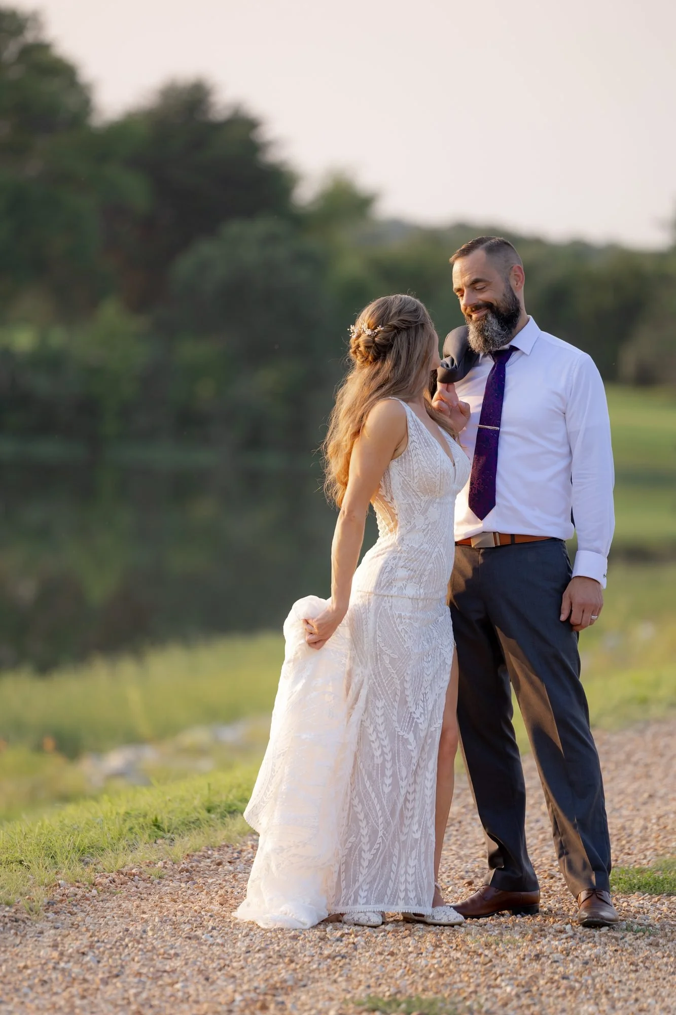 Bride and groom laughing on a gravel path by a pond at a Texas countryside wedding