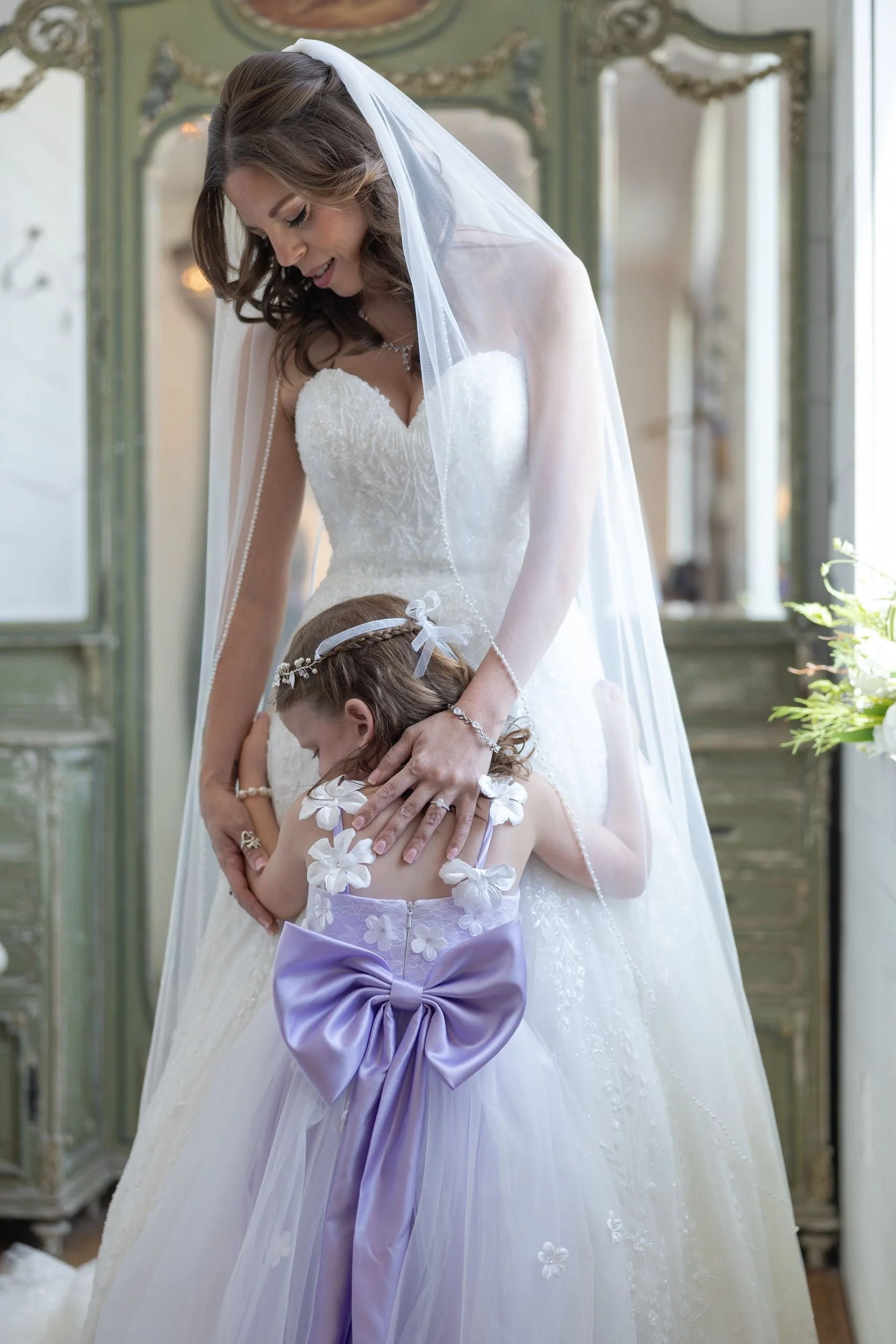 Bride hugging the flower girl in a lavender dress on Heather and Geffrey's wedding day