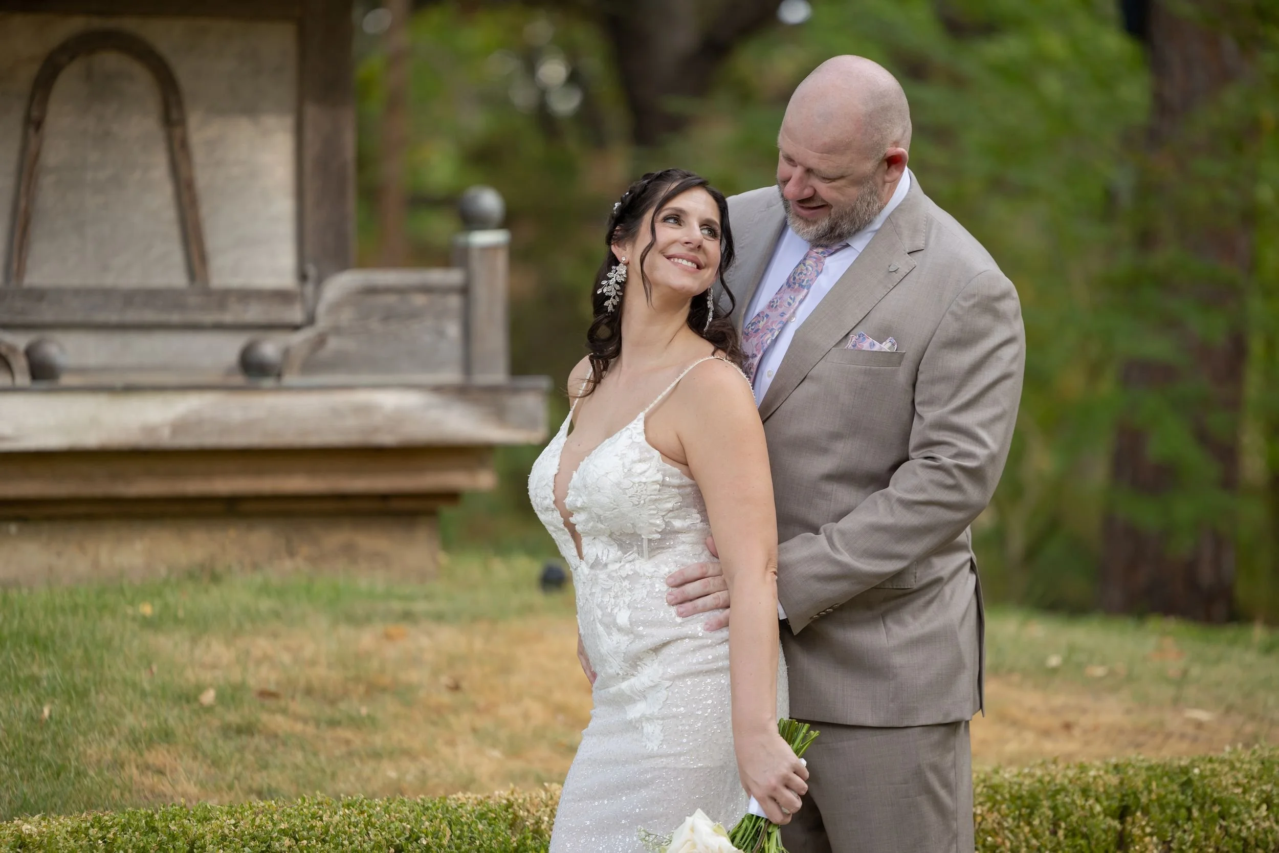 Bride and groom posing on the lawn by a pagoda-style pavilion in Fort Worth