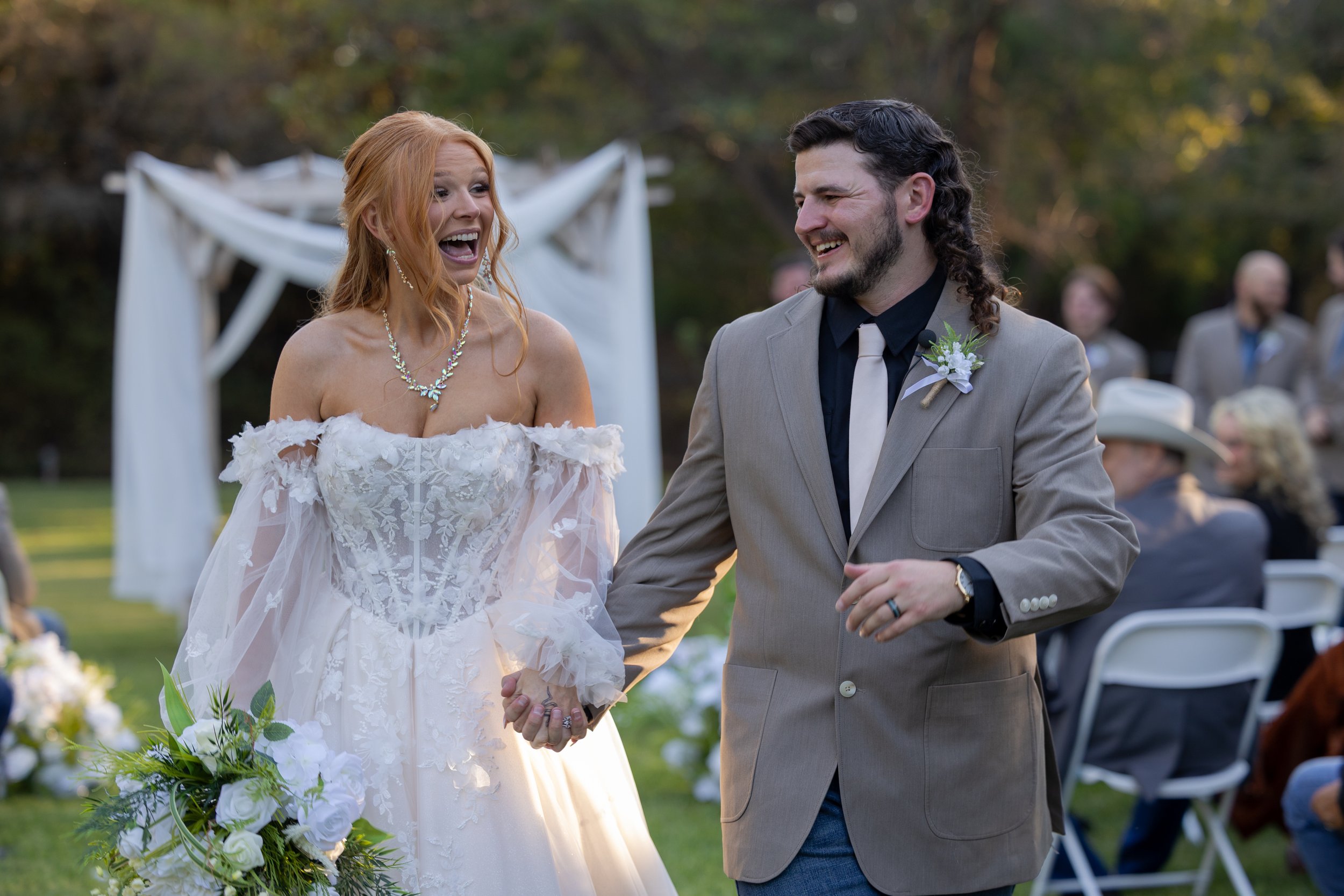 Newlywed couple holding hands and smiling after their outdoor DFW wedding ceremony