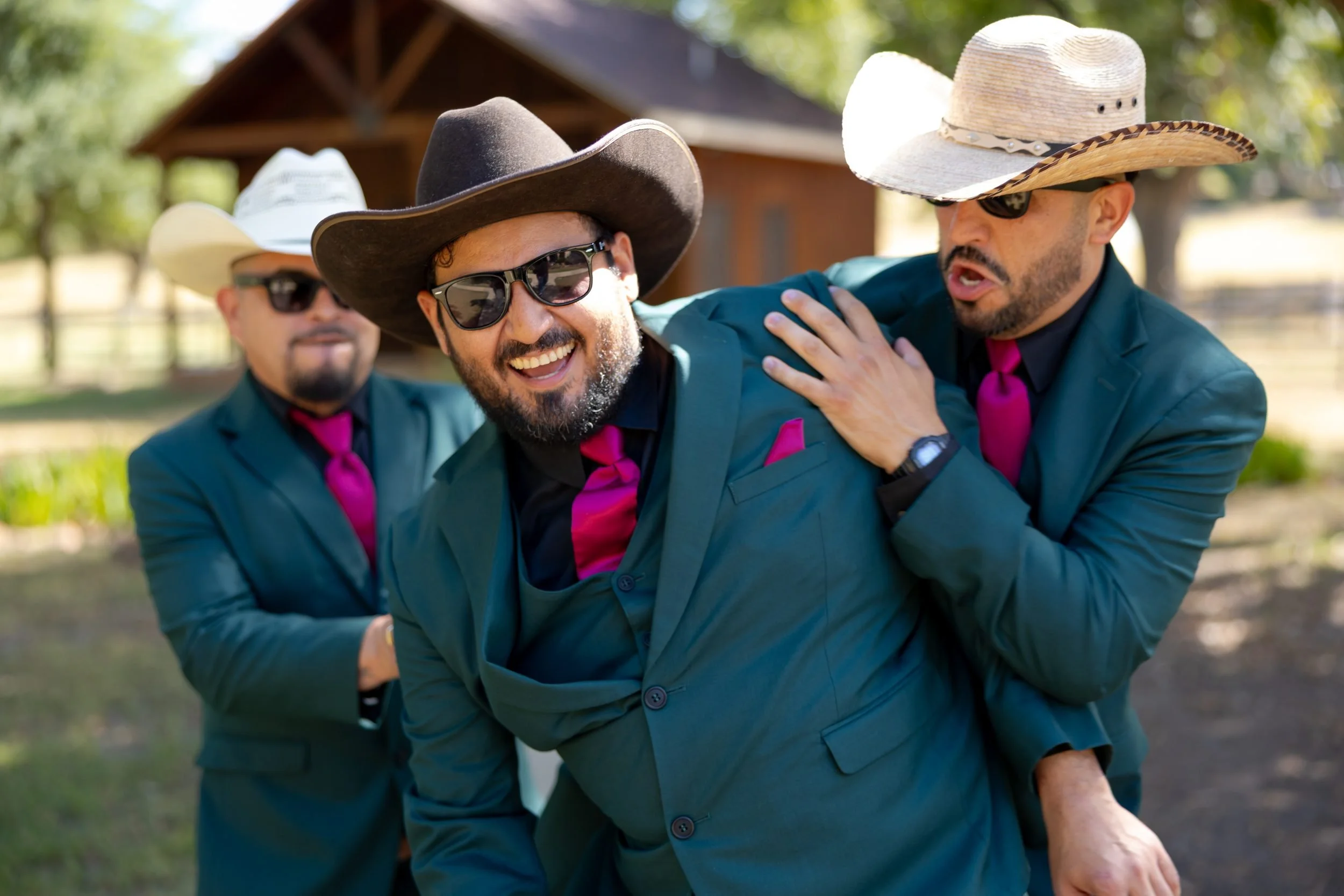 Groom laughing with his groomsmen in cowboy hats at The Orchard in Azle