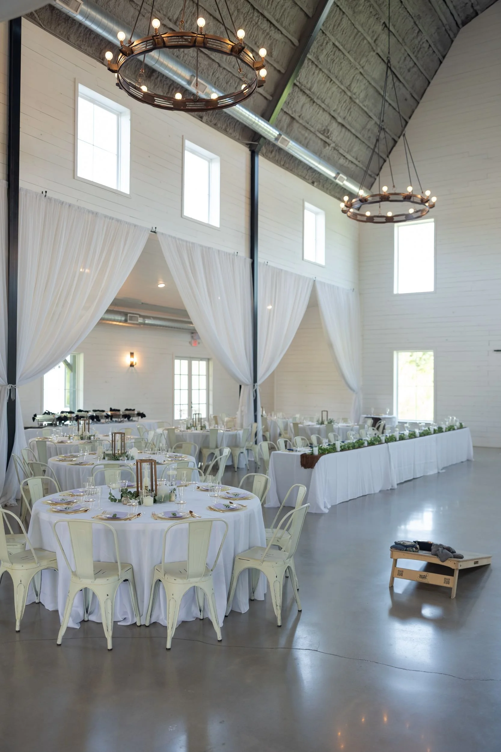 Reception barn with chandeliers and long tables at The Barn at Paradise Place in Weatherford