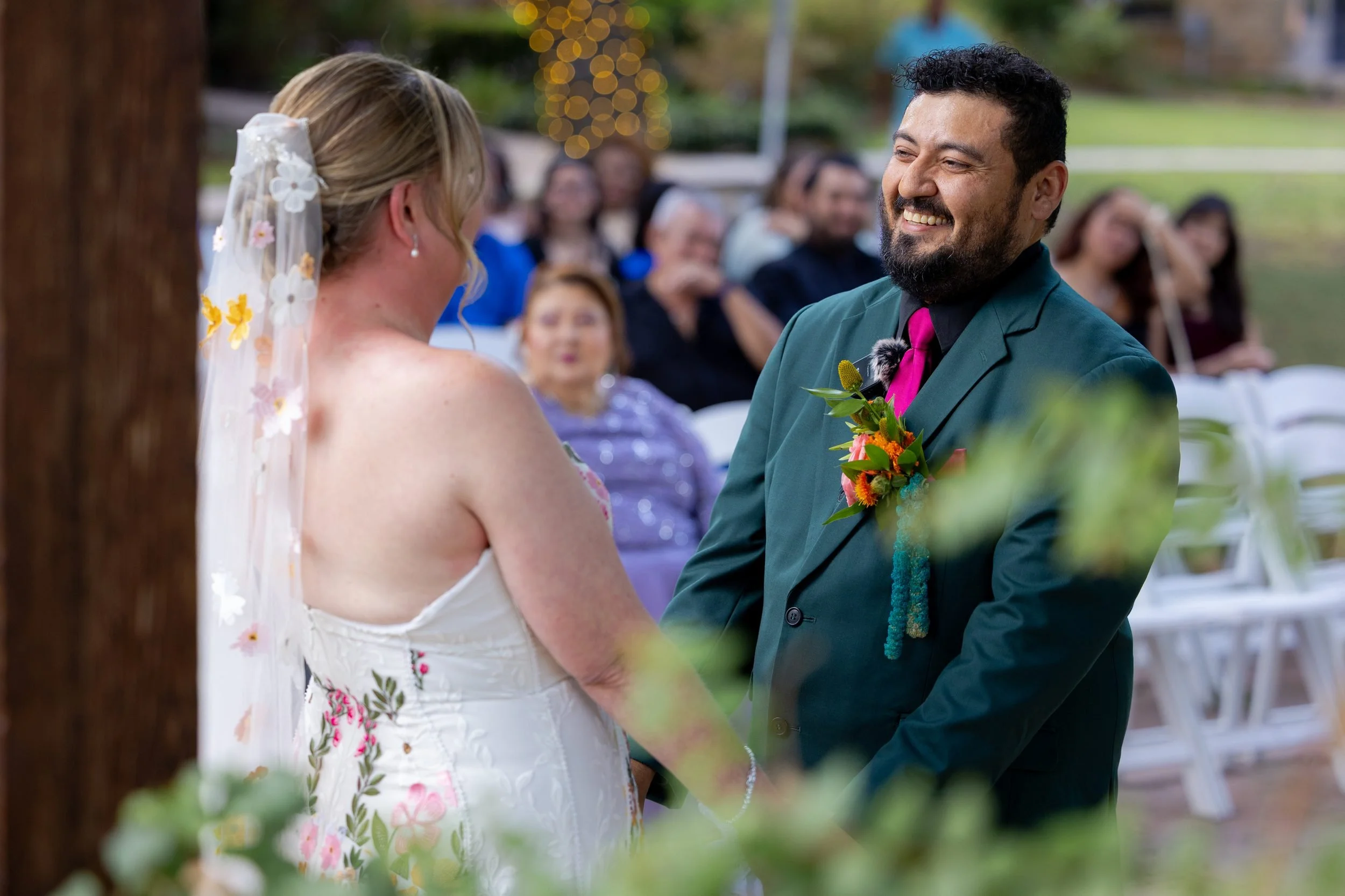 Bride and groom smiling at their guests during the ceremony at The Orchard
