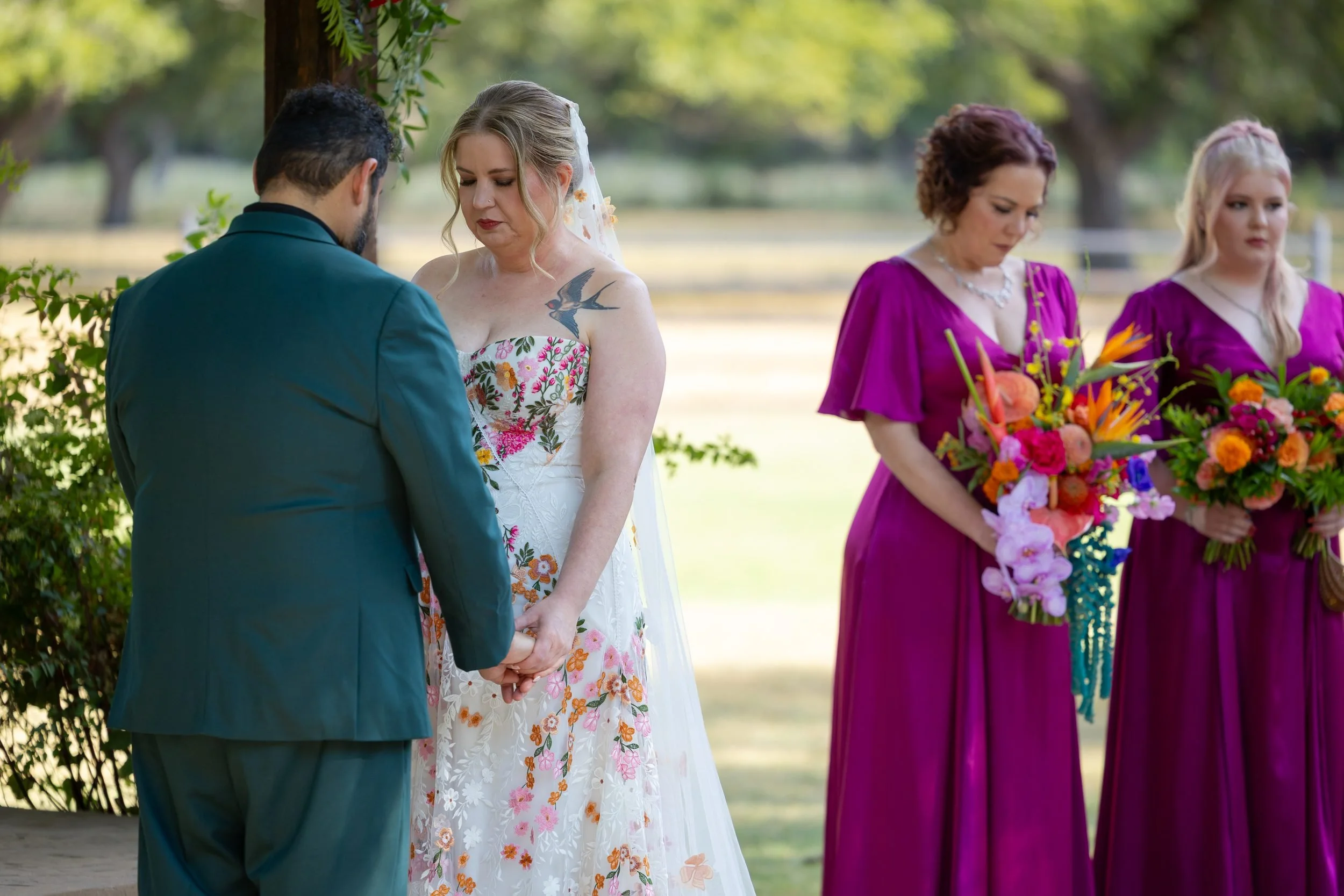 Carita and Miguel at the altar with bridesmaids in magenta dresses