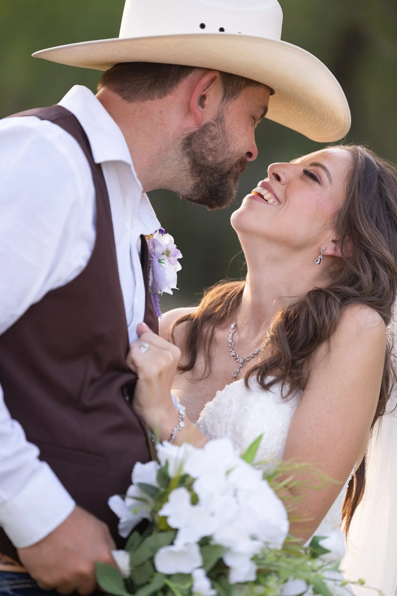 Cowboy groom and bride laughing together at their western Texas wedding