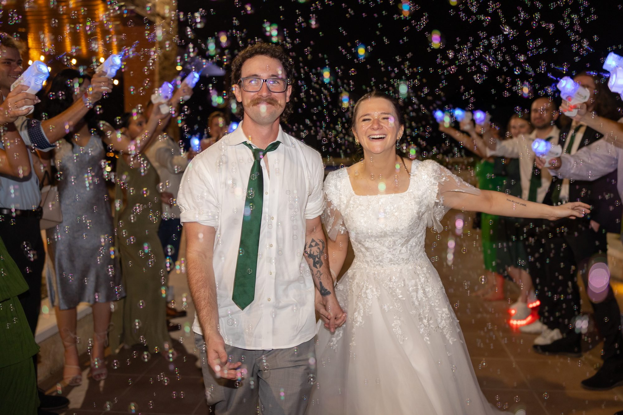 Bride and groom walk through a bubble send-off at their Fort Worth wedding reception