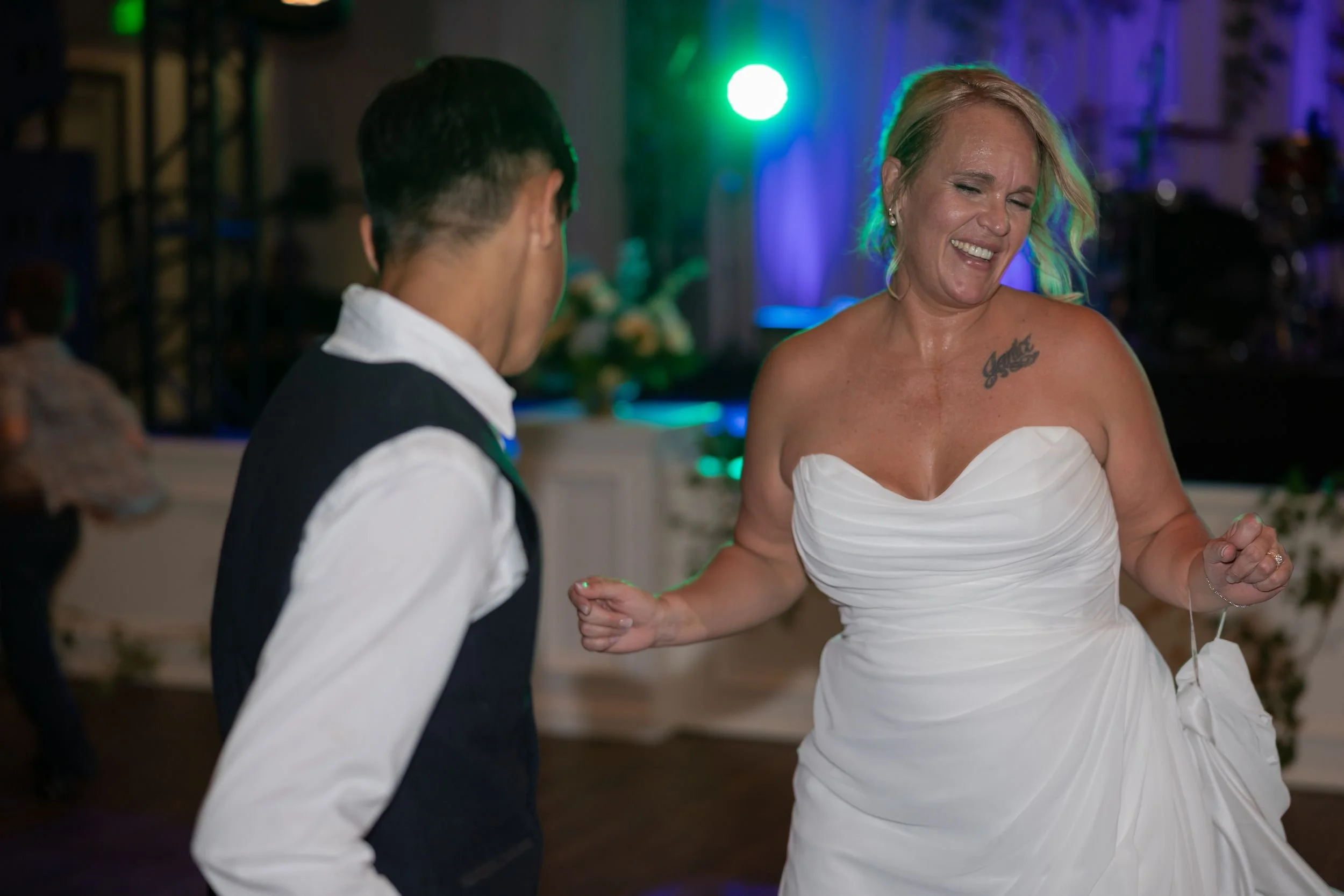 Bride dancing under colorful lights at her Dove Ridge Vineyard reception