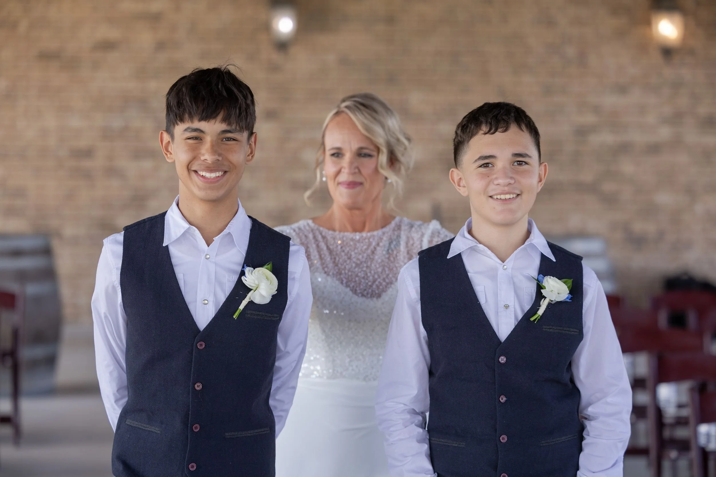 Bride posing with two young groomsmen in navy vests