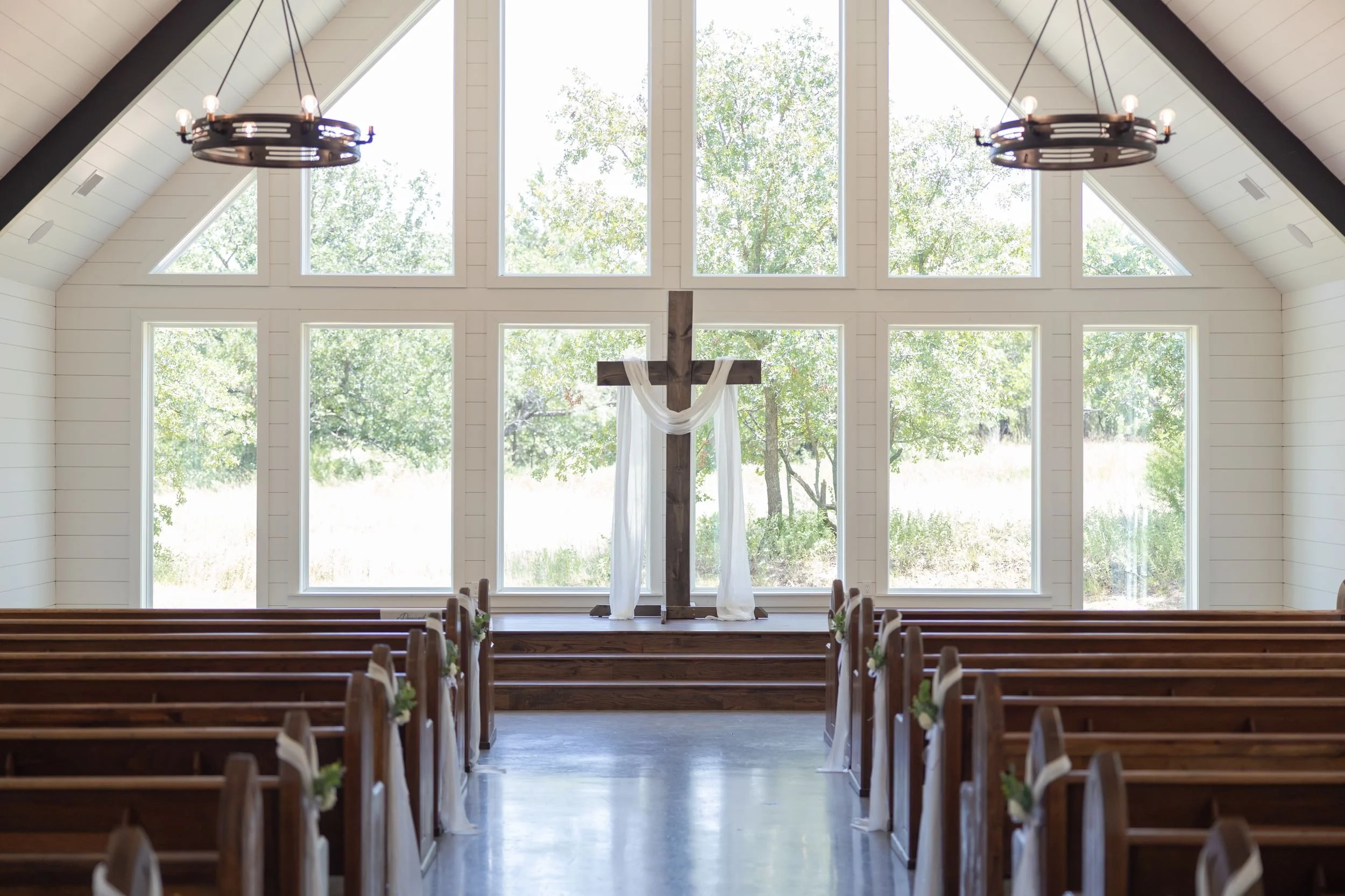 Bright chapel interior with wooden pews at The Barn at Paradise Place wedding venue
