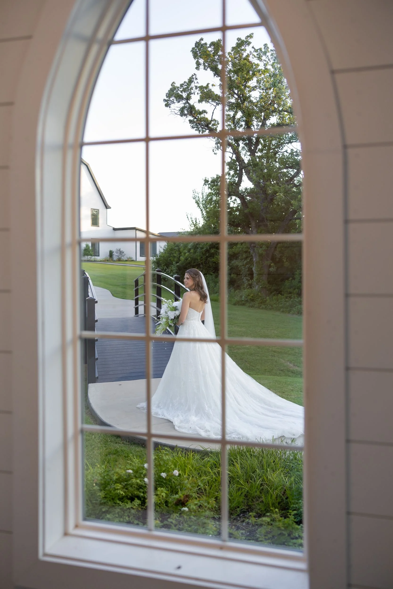Heather's wedding dress hanging in an arched window at The Barn at Paradise Place in Weatherford