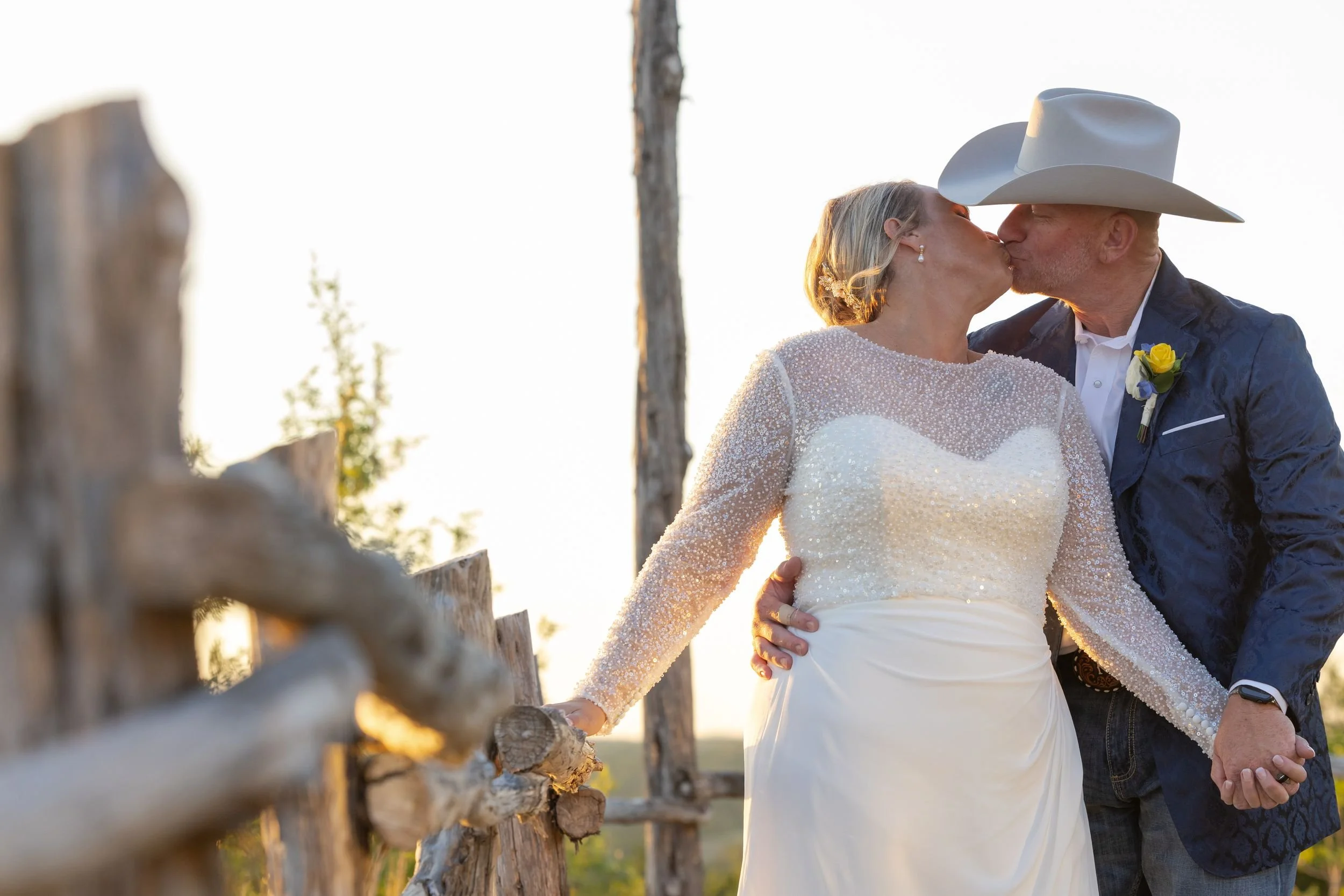 Bride and groom by a wooden fence during golden hour portraits in Weatherford, Texas