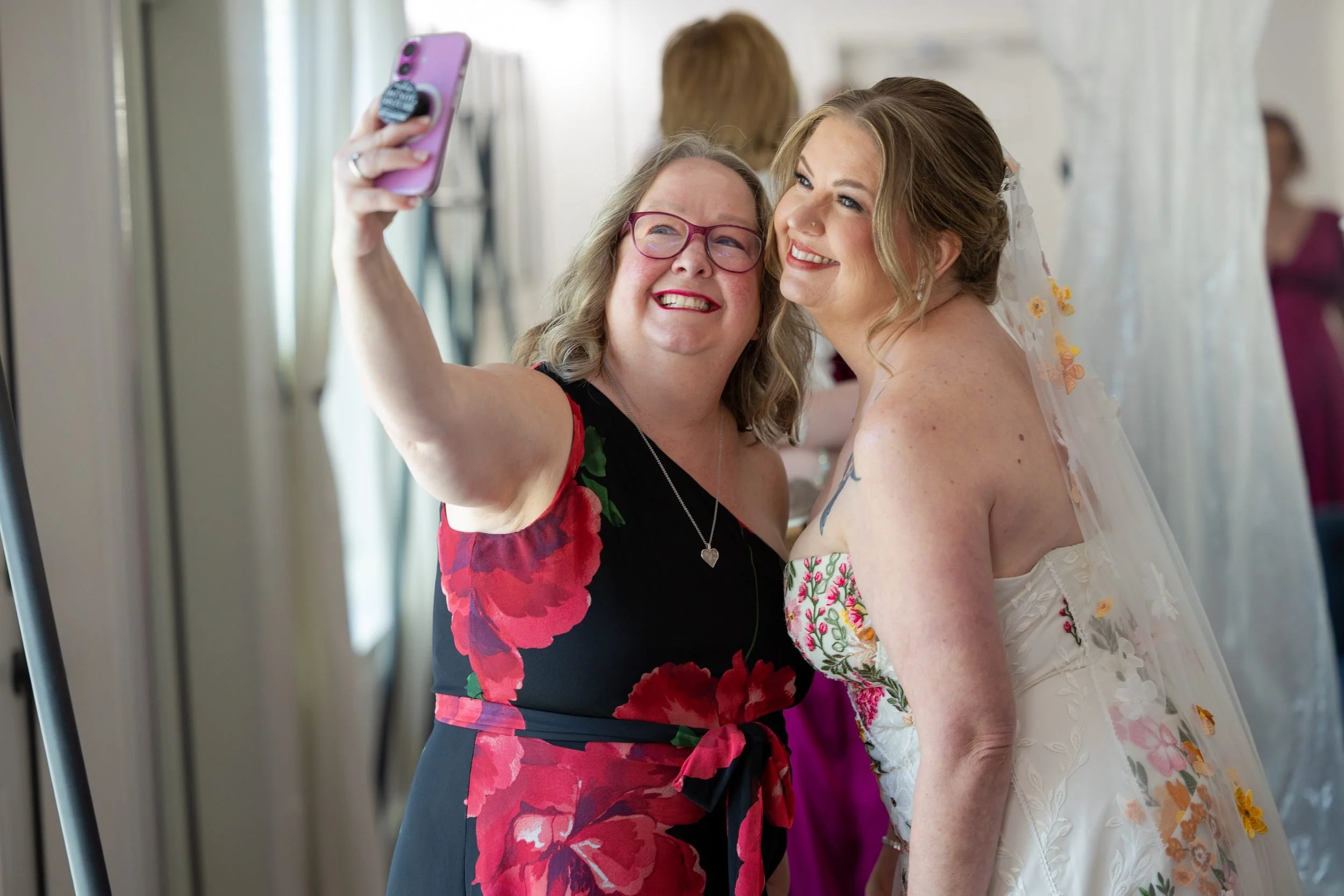 Bride taking a selfie with a bridesmaid while getting ready at The Orchard